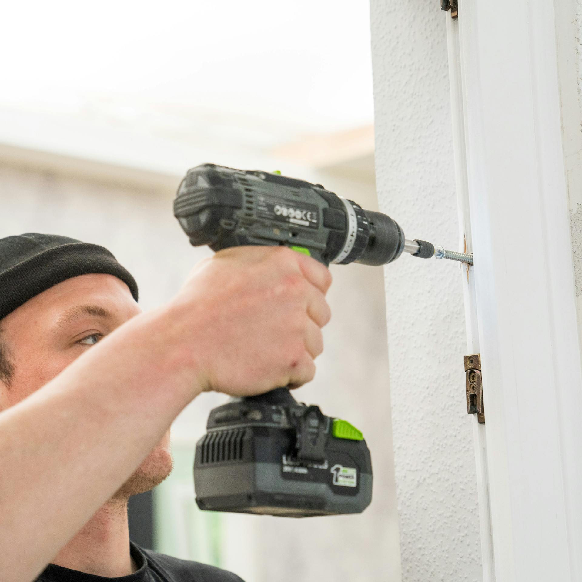 Heimwerker entfernt Scharniere mit einem Schraubendreher.