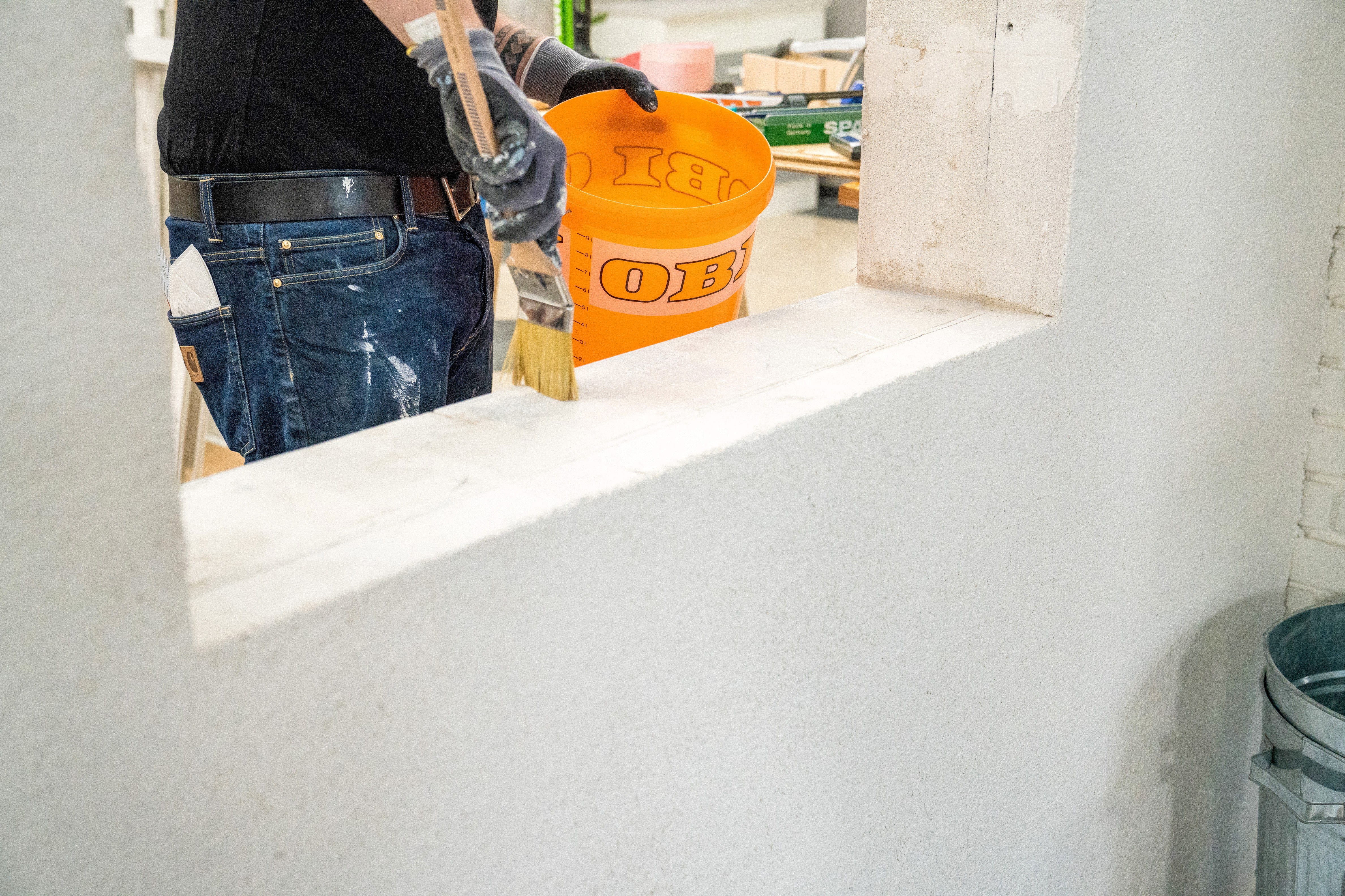 Handwerker trägt bis zur Markierung Tiefgrund auf.