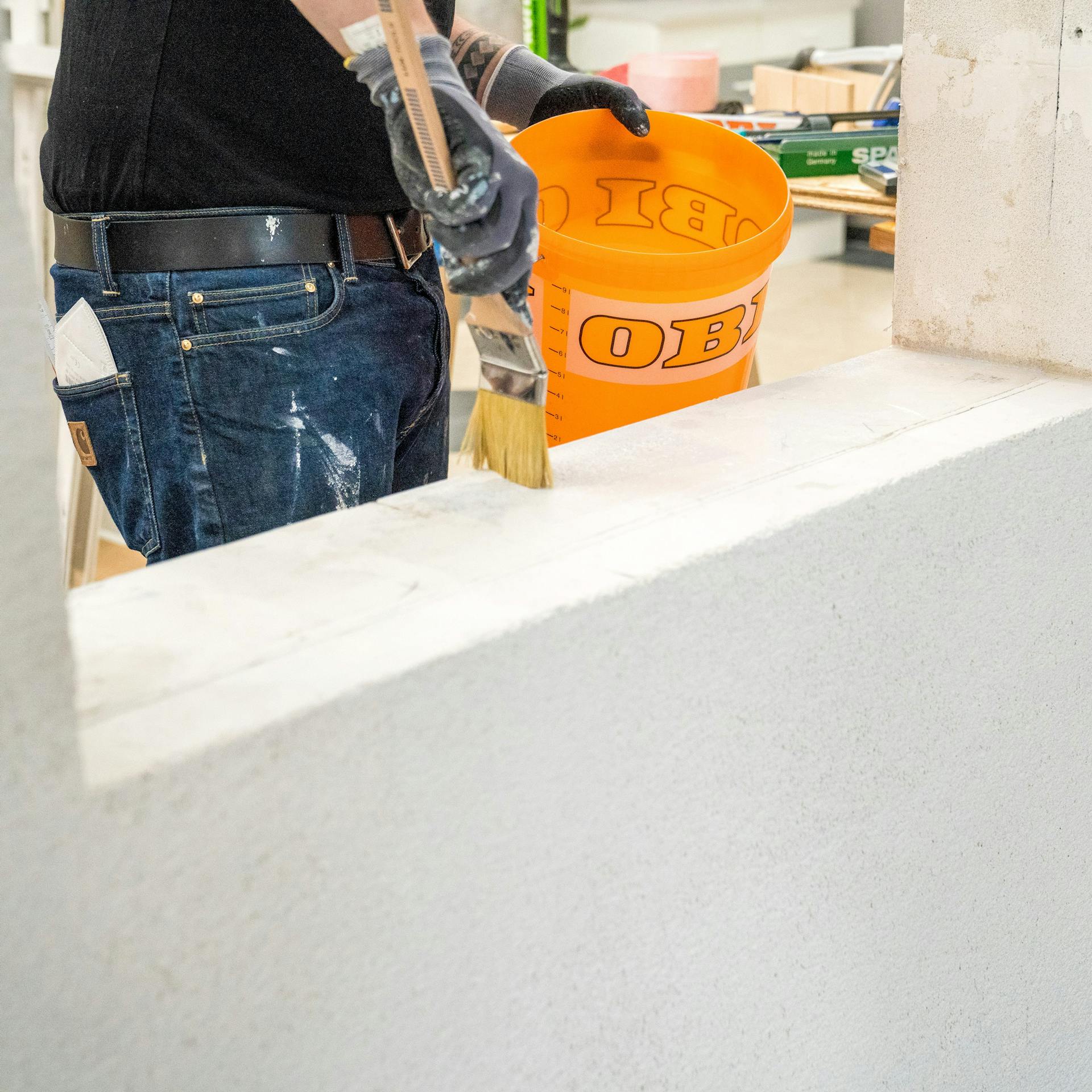 Handwerker trägt bis zur Markierung Tiefgrund auf.