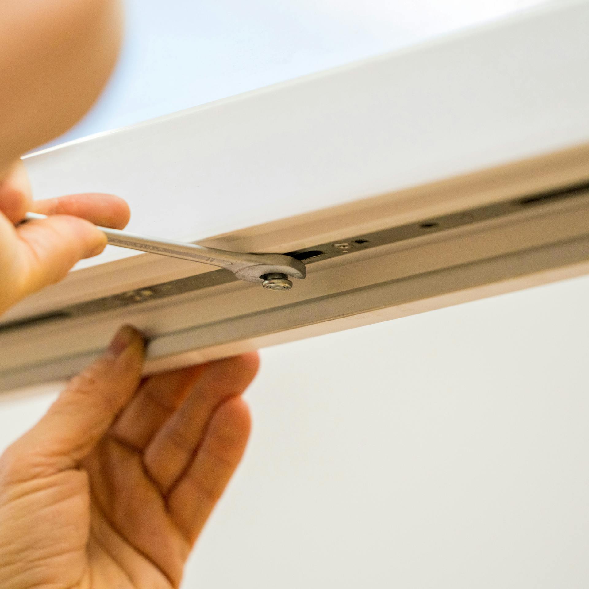 Jemand stellt den Anpressdruck unten am Fenster ein.