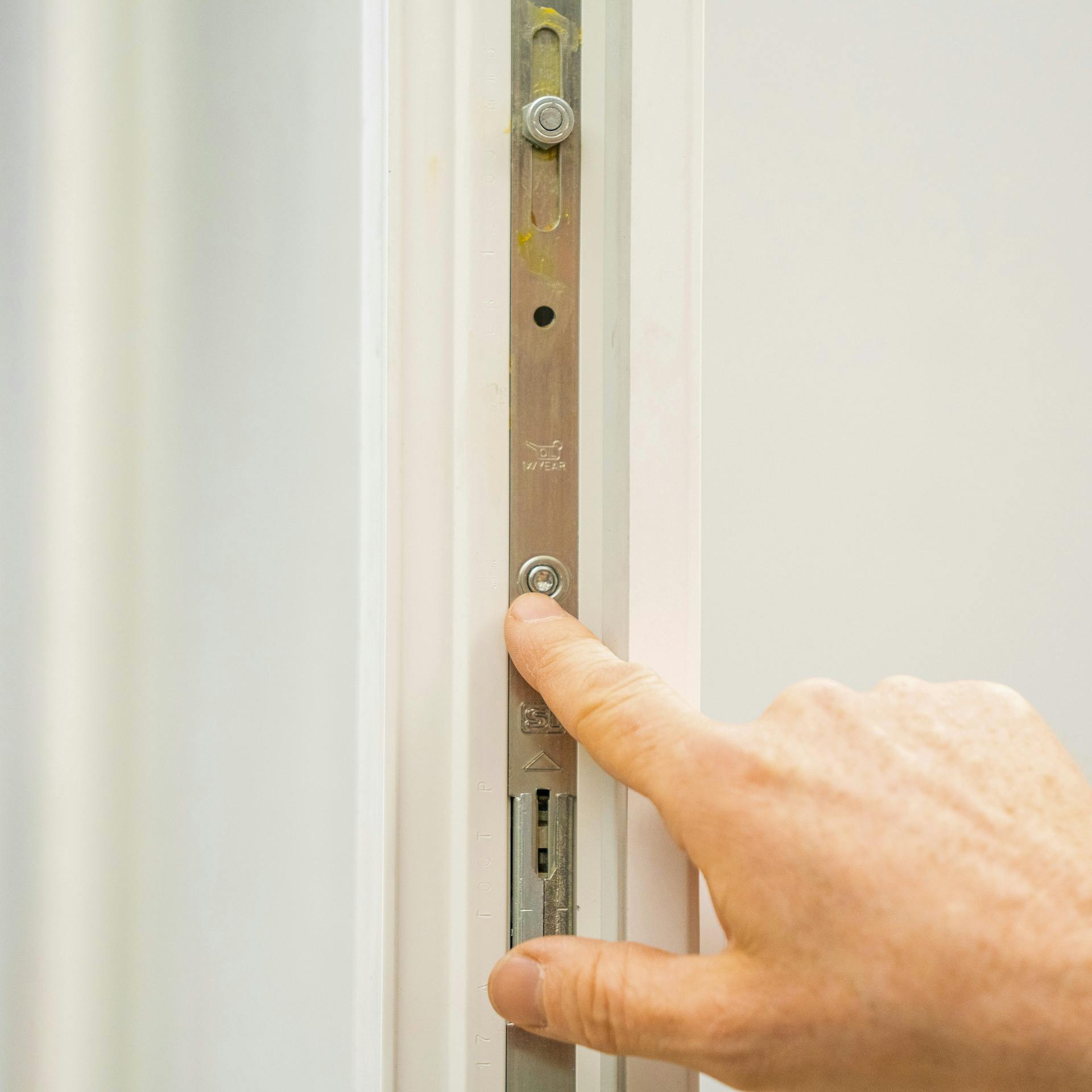 Jemand zeigt auf den Schließzapfen eines Fensters.