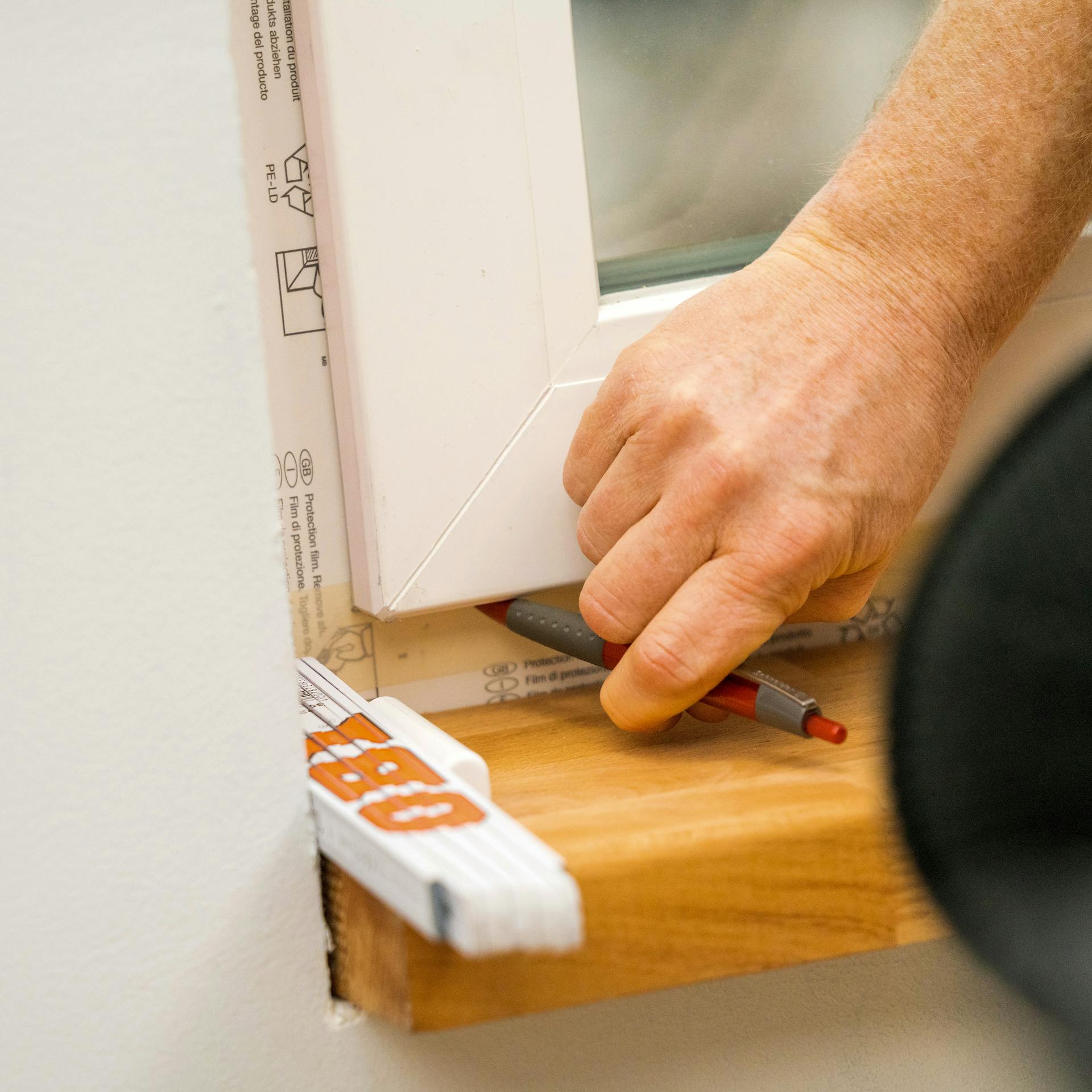 Jemand markiert die Position des Fensterflügels.