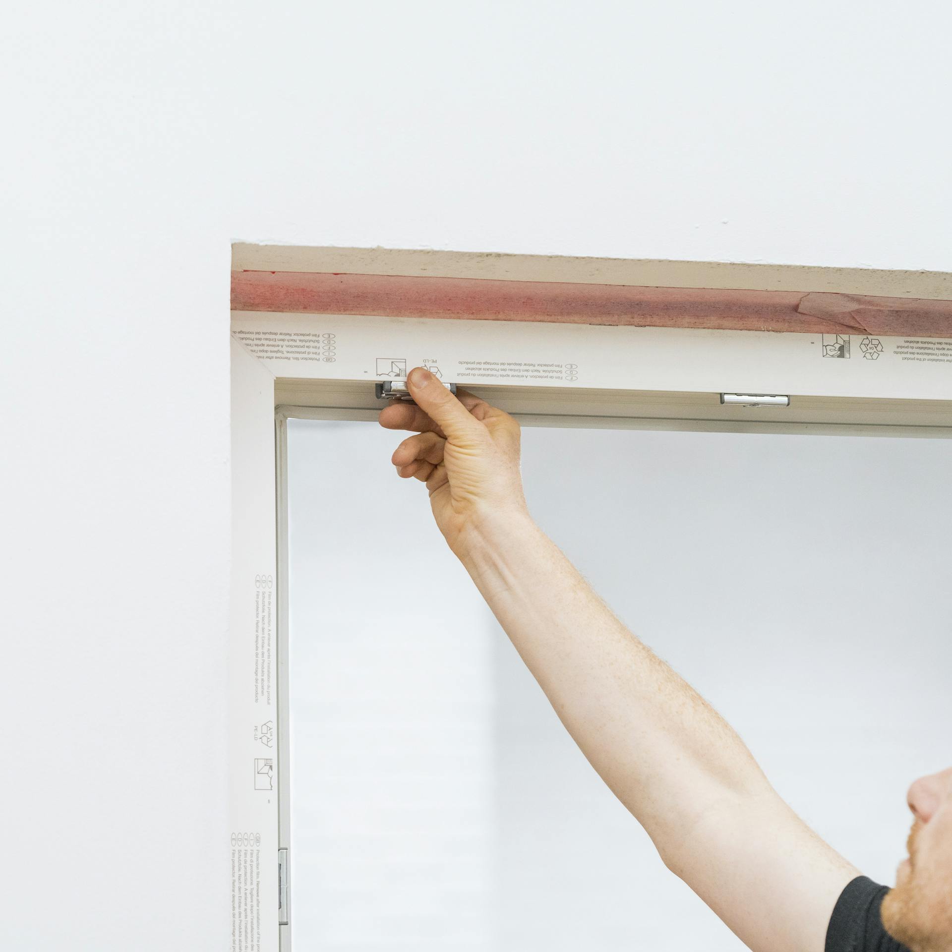 Ein Mann prüft die Beschläge eines Fensters.