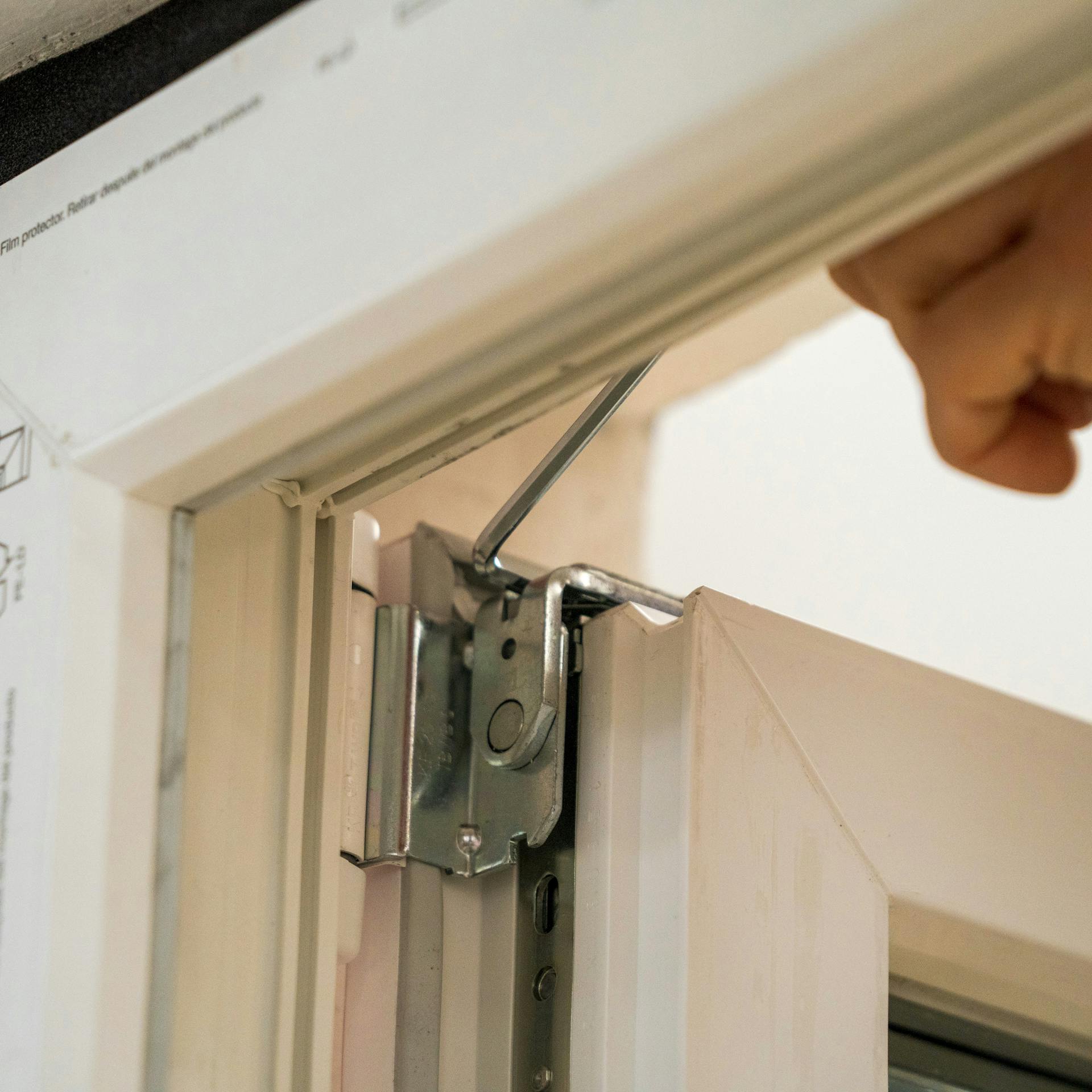 Jemand stellt einen Fensterflügel am Scherenlager ein.