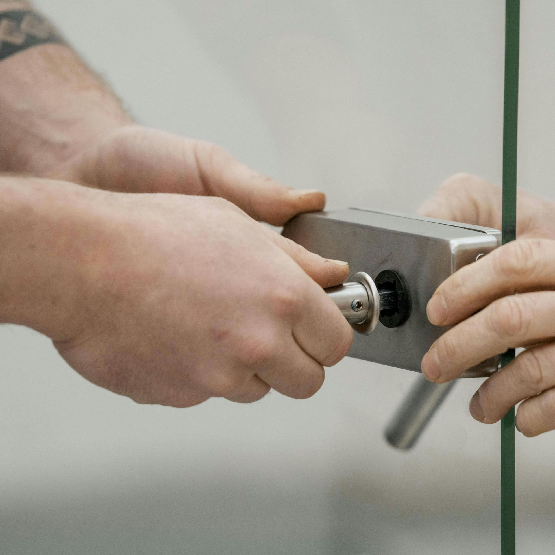 Zwei Personen montieren die Klinken einer Glastür