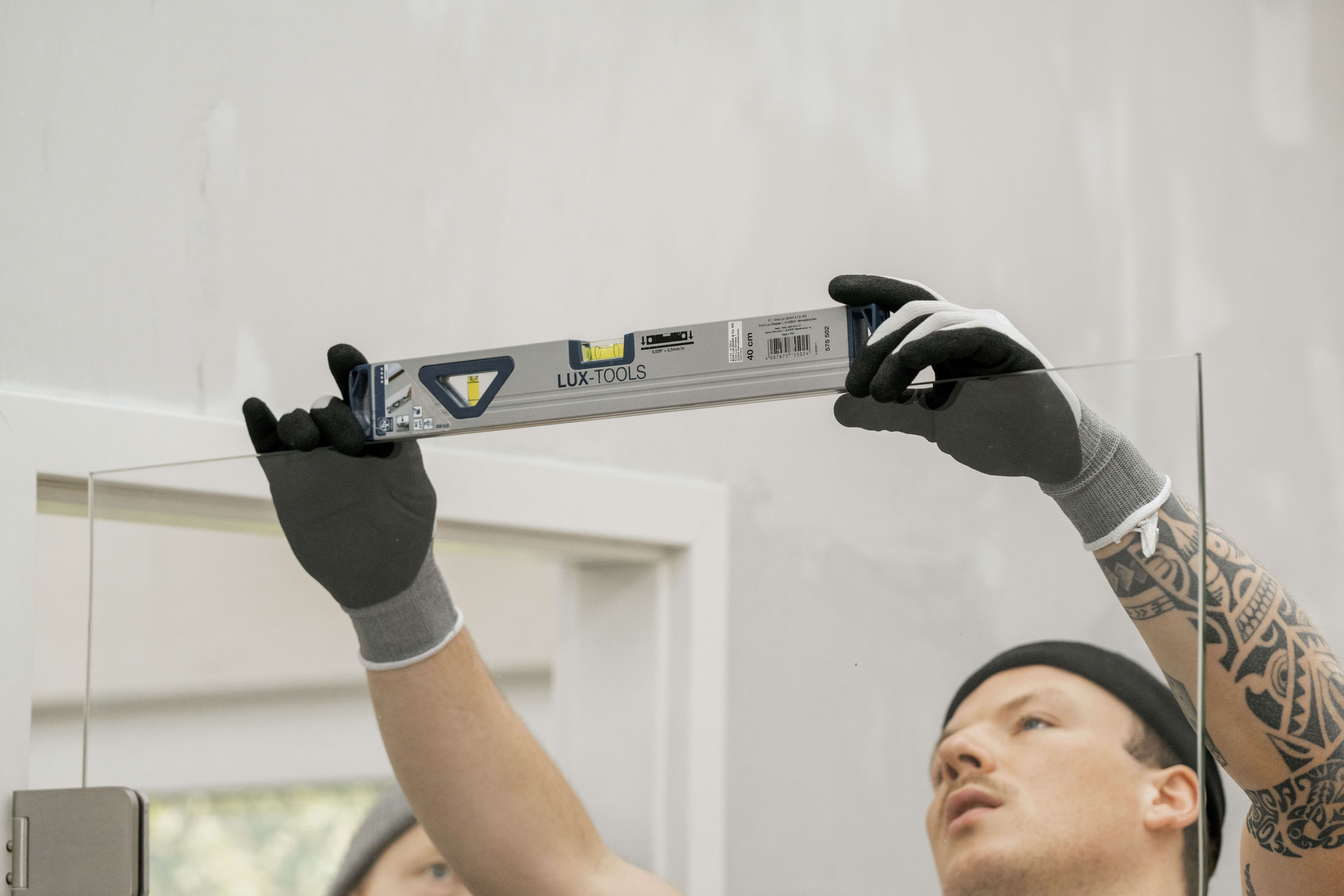 Ein Mann überprüft die Ausrichtung einer Glastür mit einer Wasserwaage