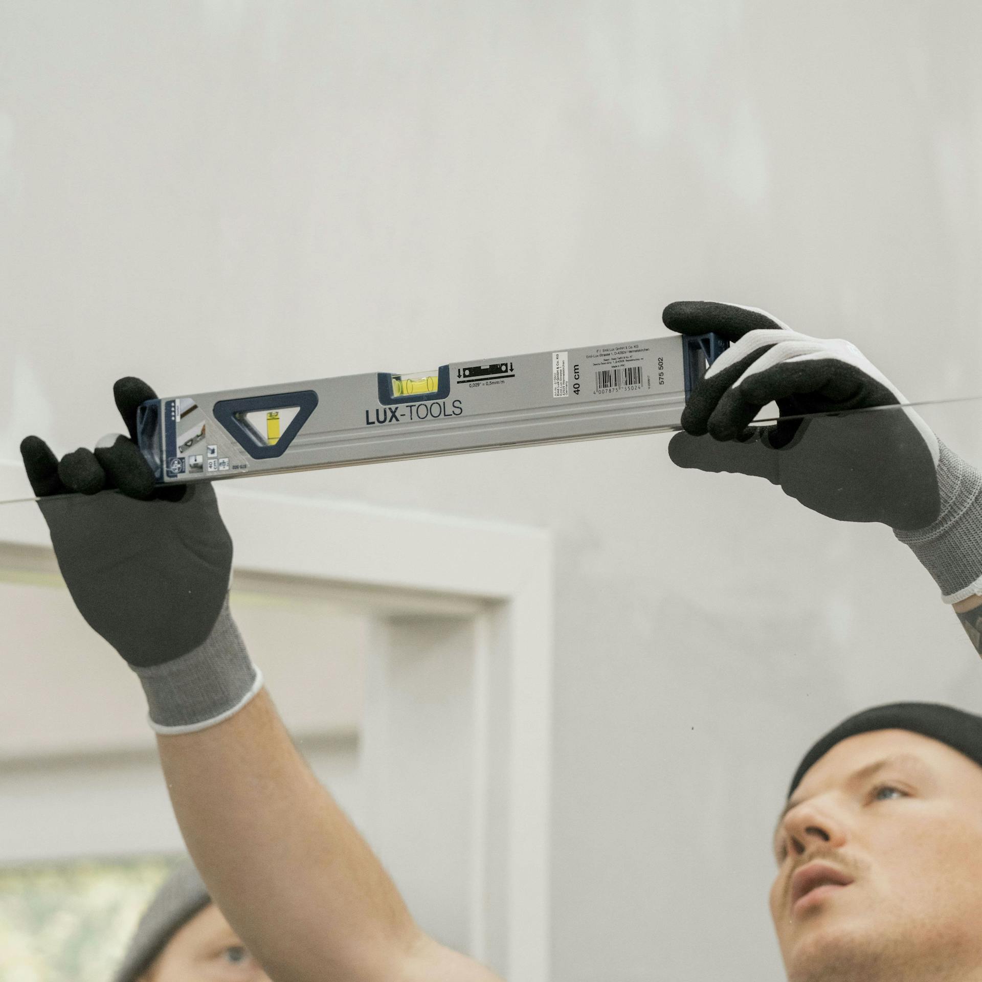 Ein Mann überprüft die Ausrichtung einer Glastür mit einer Wasserwaage