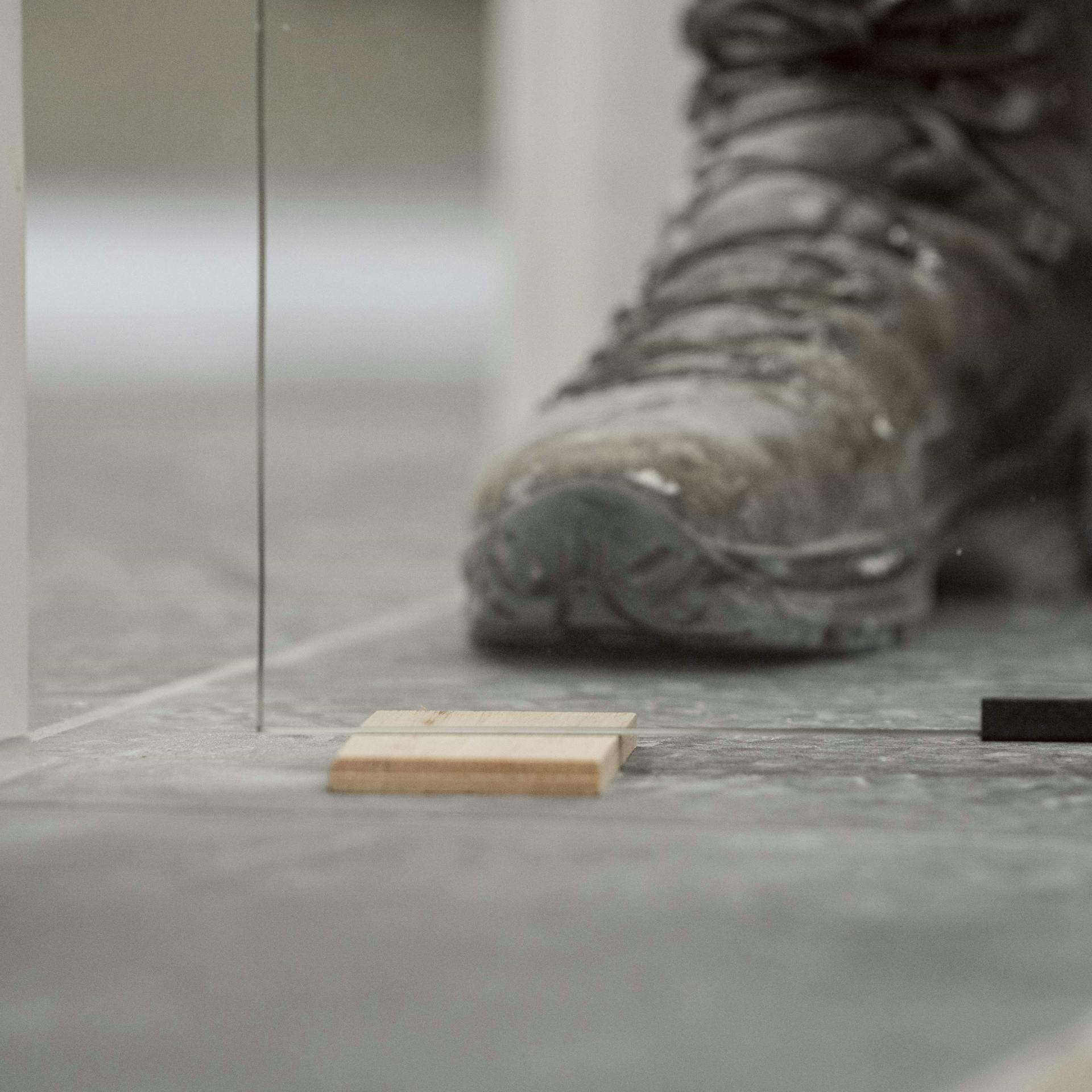 Jemand stellt eine Glastür auf einem Holzkeil ab