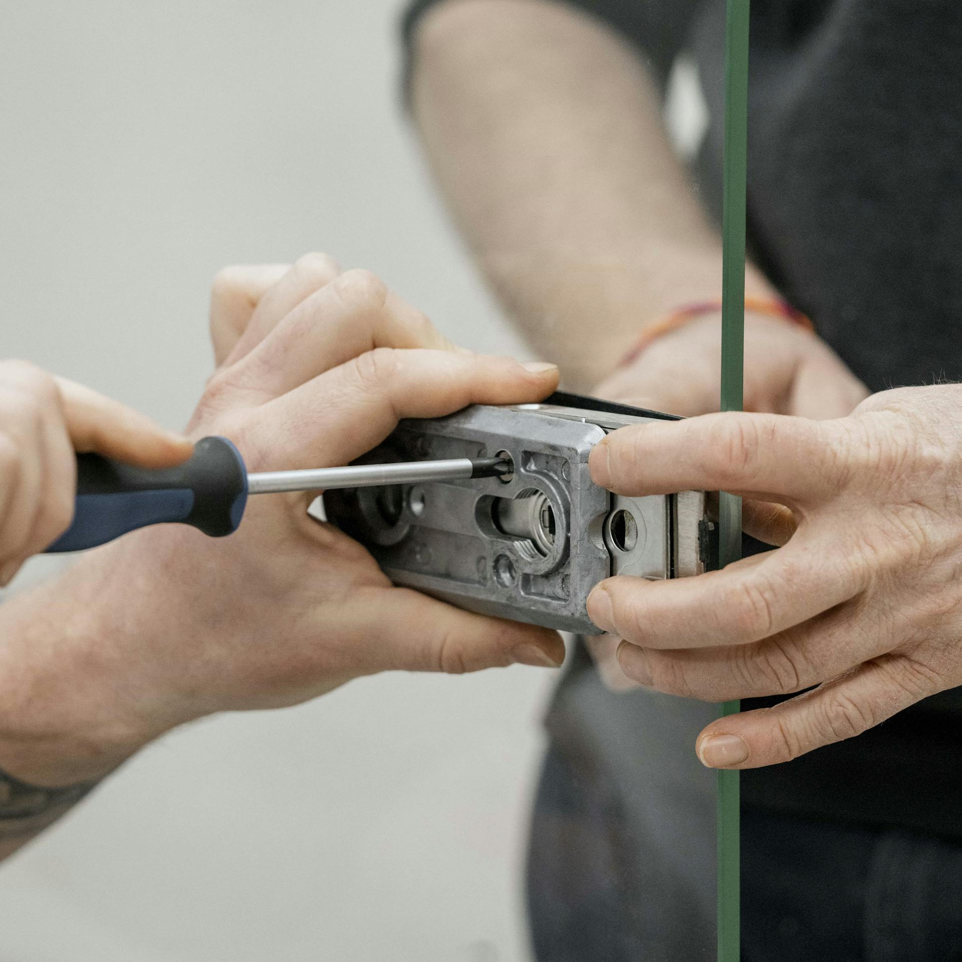 Zwei Personen montieren einen Schlosskasten an einer Glastür