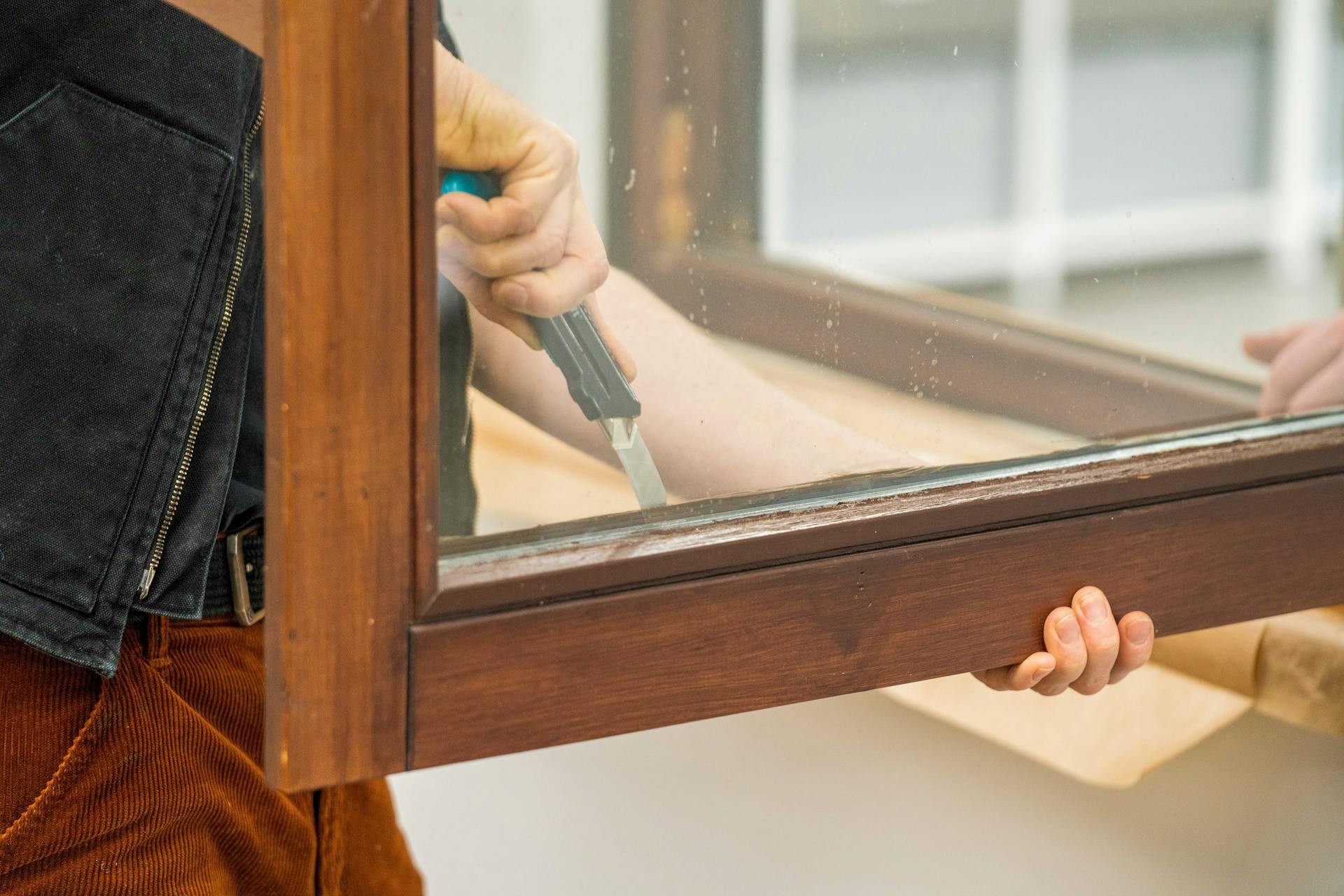 Un amante del fai da te rimuove le guarnizioni da una finestra in legno.