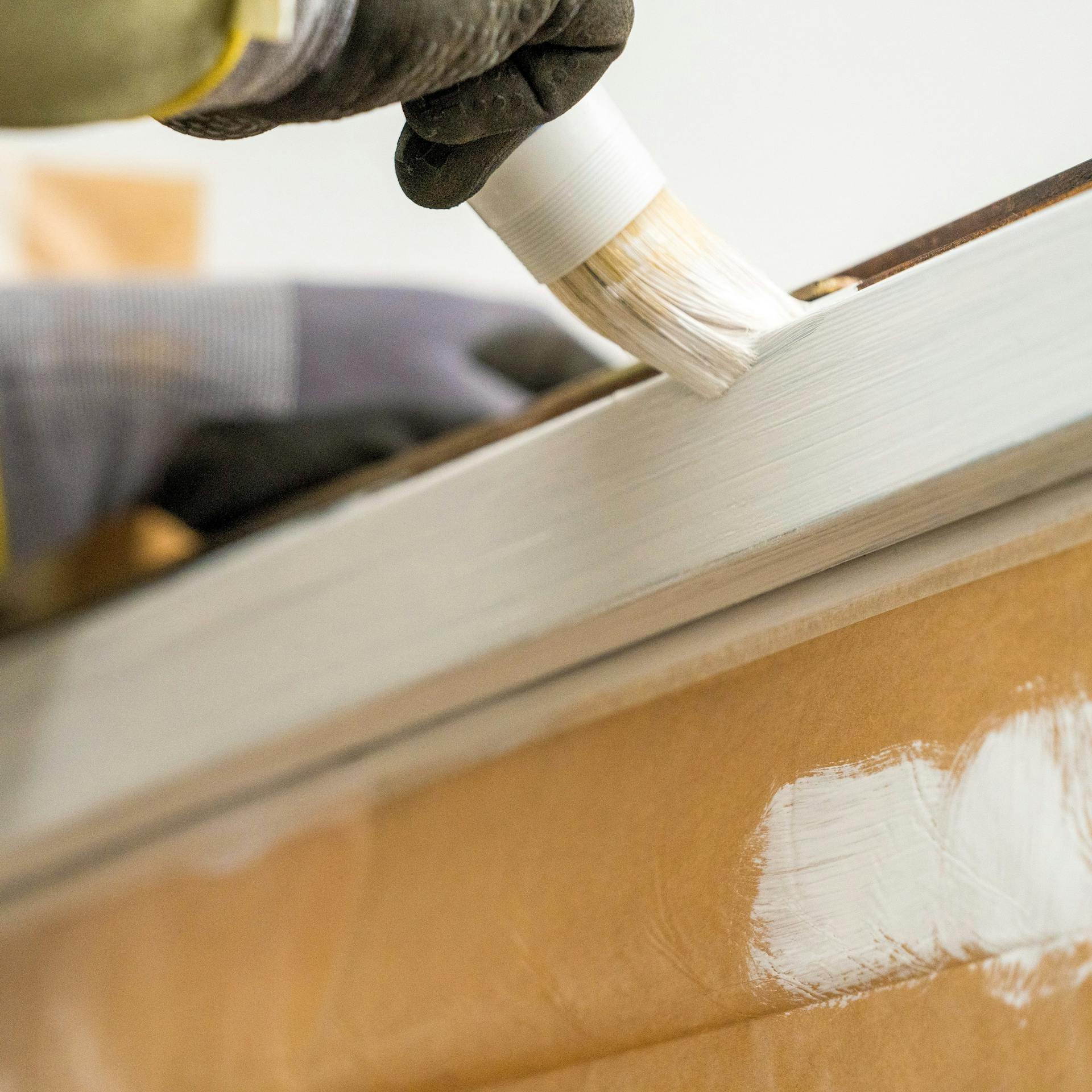 Heimwerker streicht ein Fenster mit PU-Lack.