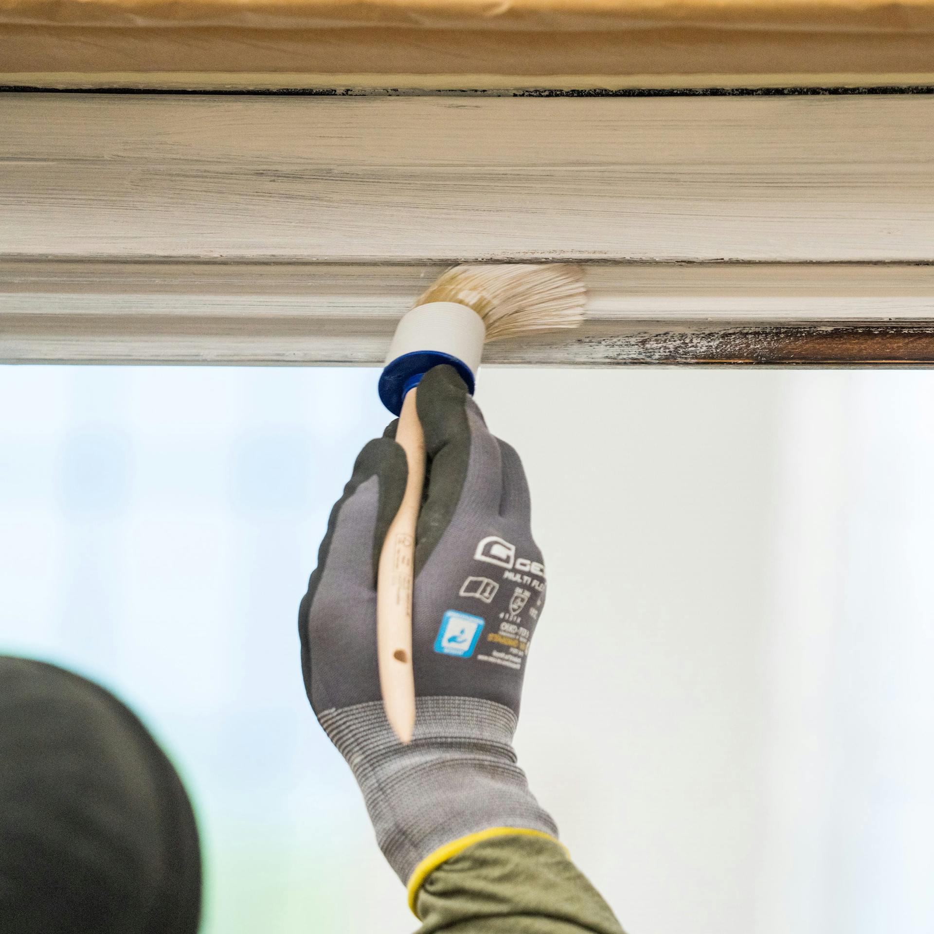 Heimwerker bestreicht einen Fensterrahmen mit Vorlack.