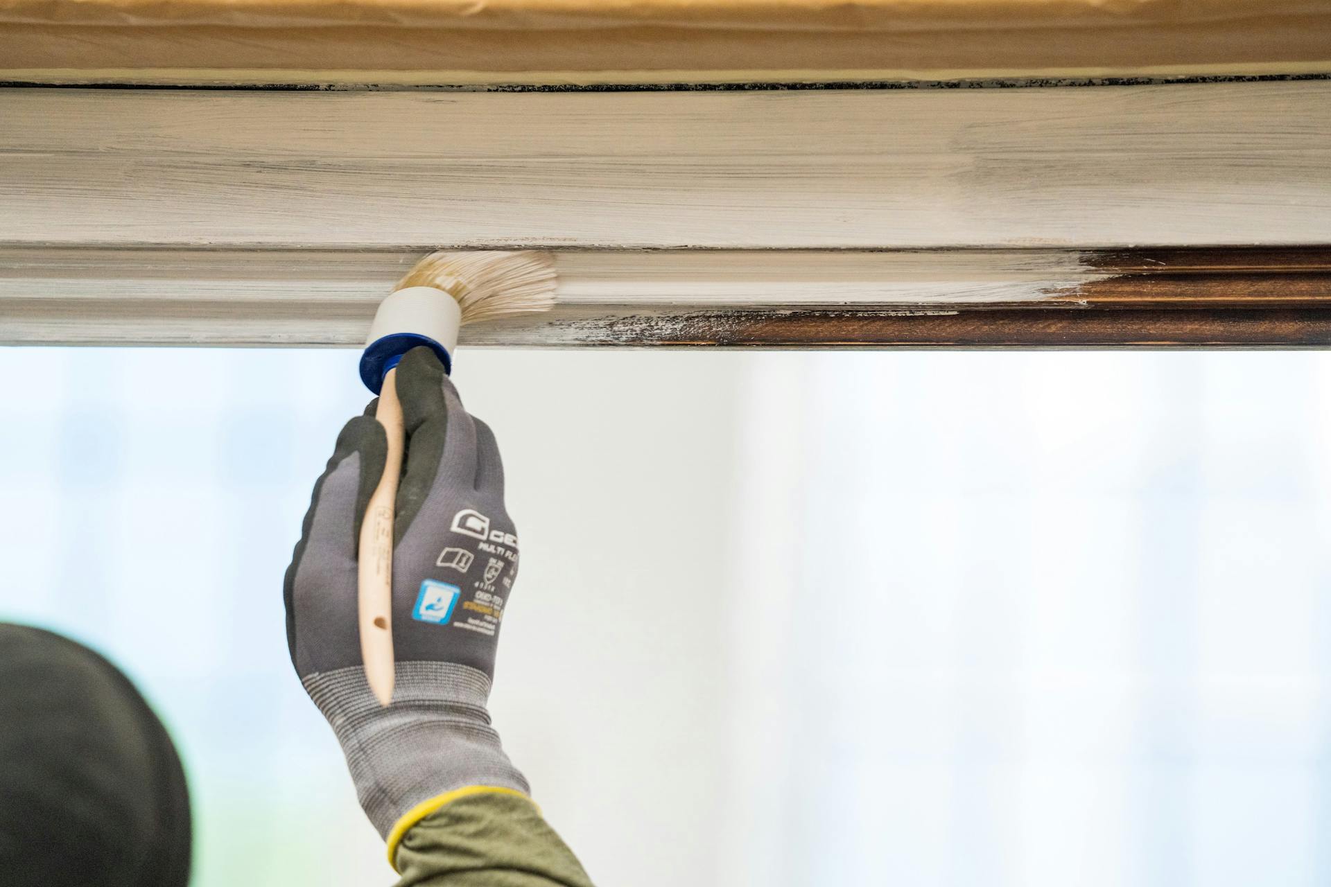 Un amante del fai da te applica il primer sul telaio di una finestra.