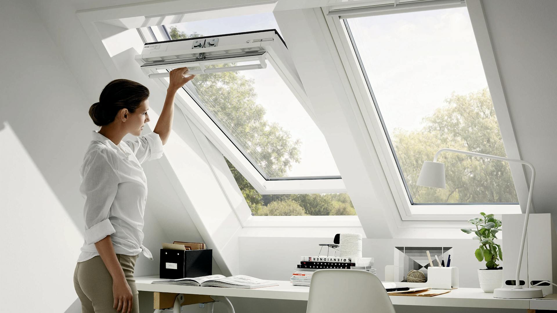 Richtig lüften; Frau öffnet Dachfenster an einem Arbeitsbereich.
