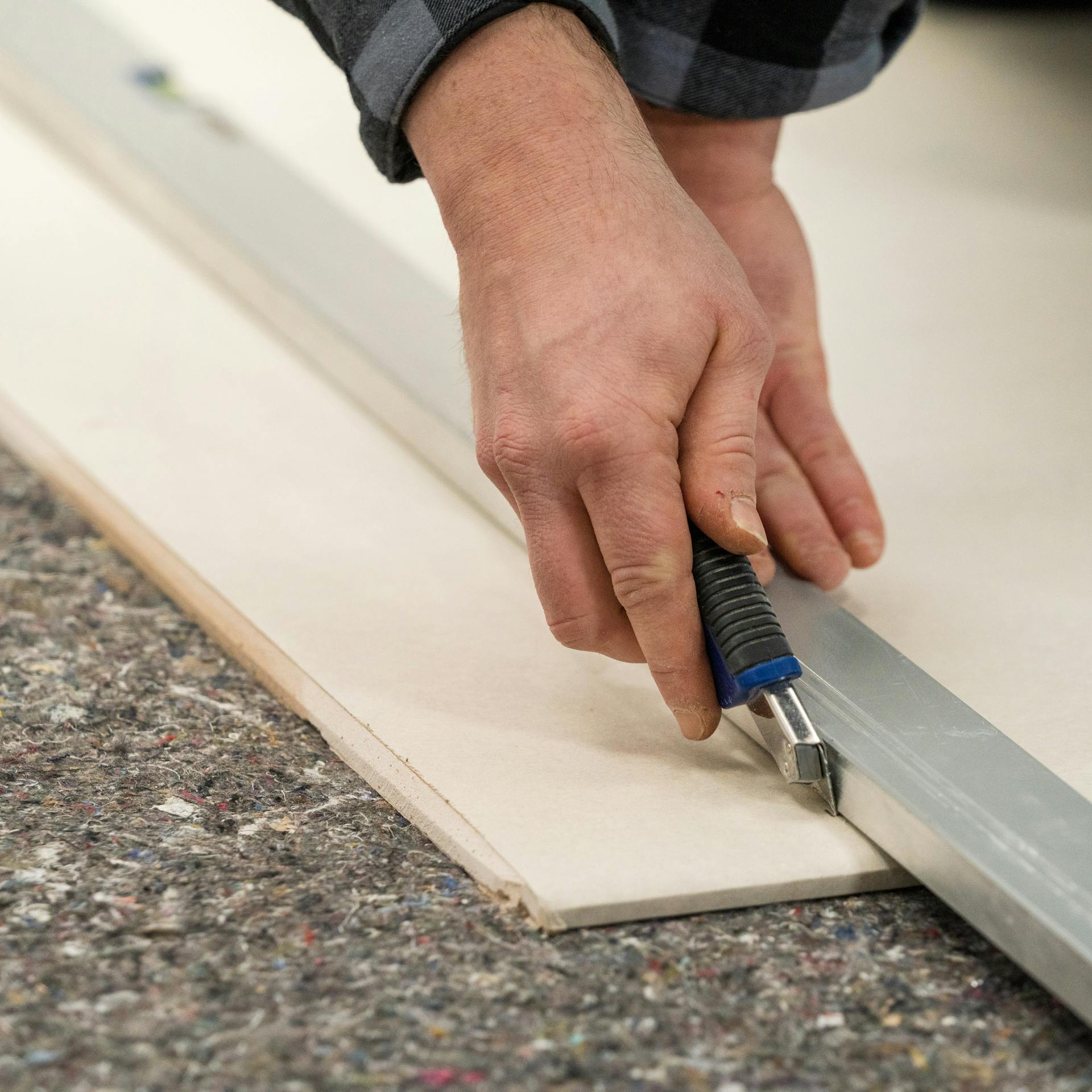 Handwerker schneidet eine Gipskartonplatte mit einem Cuttermesser zu.