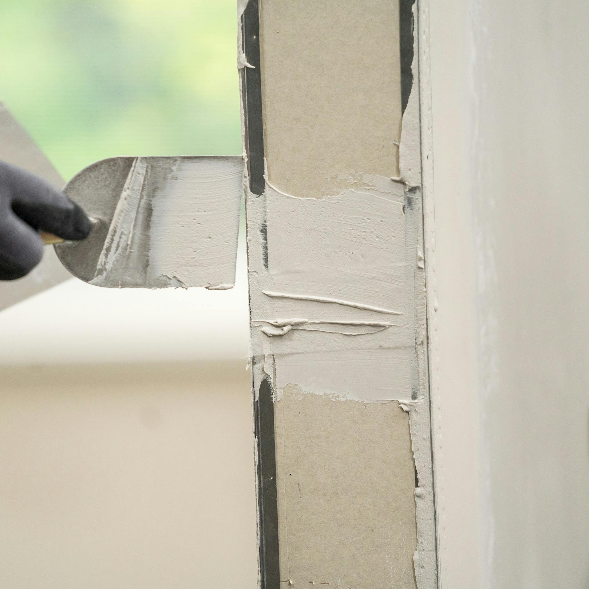 Heimwerker verspachtelt die Türöffnung mit Füllspachtel.
