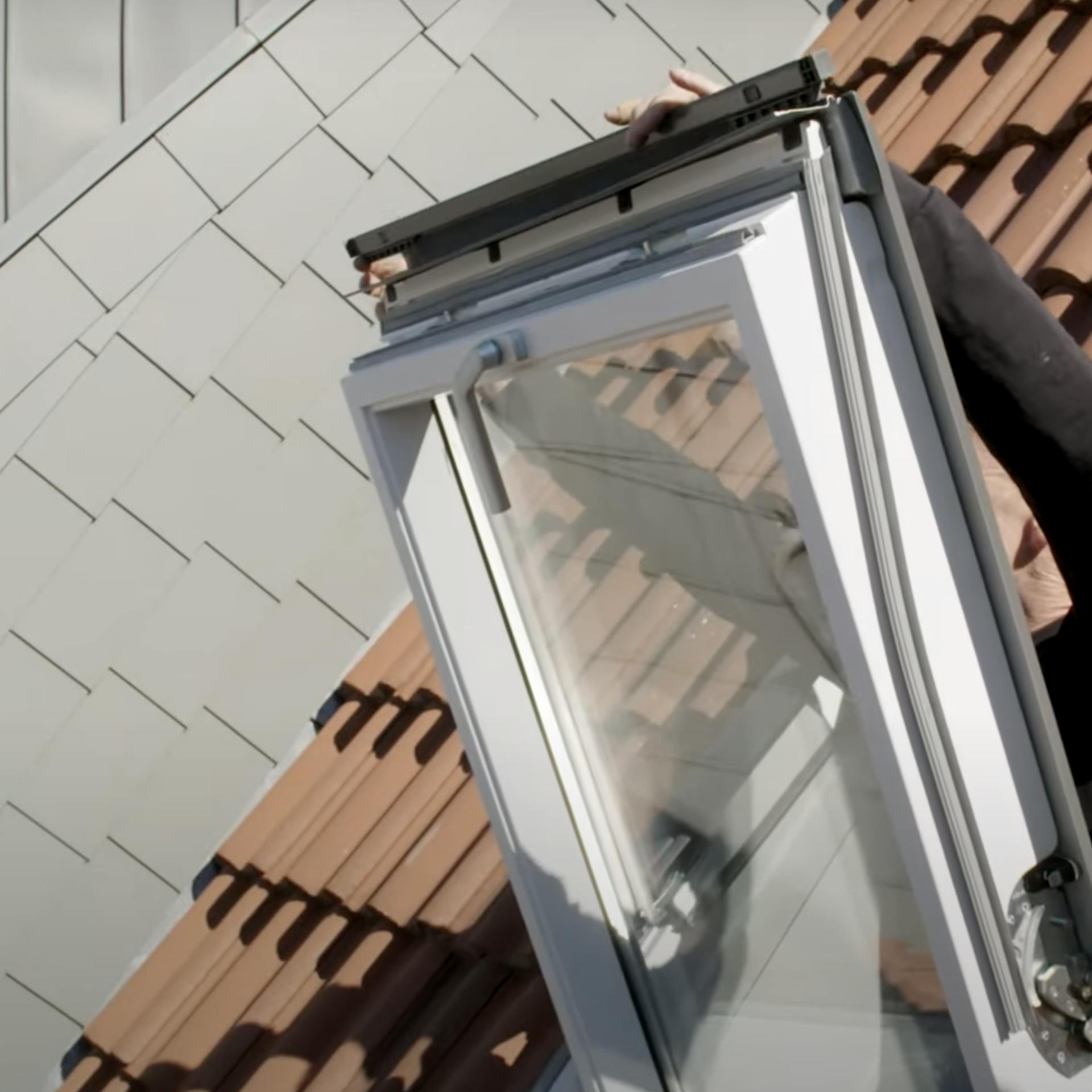 Ein Mann dreht sein Fenster ein, um den Rahmen des Solar-Rollos zu befestigen.