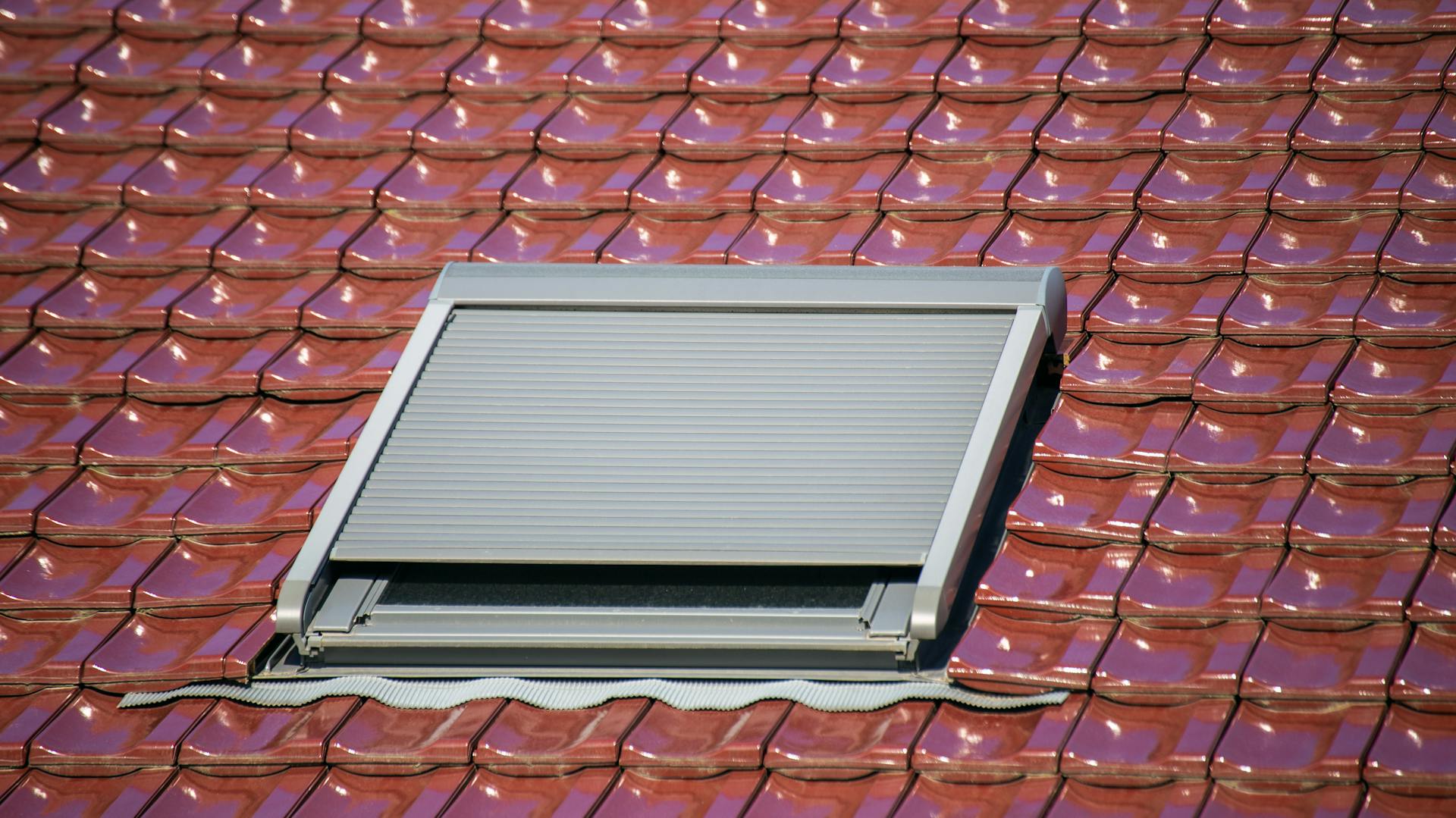 Ein Mann setzt die Abdeckung des Solarrollos auf den Fensterrahmen.