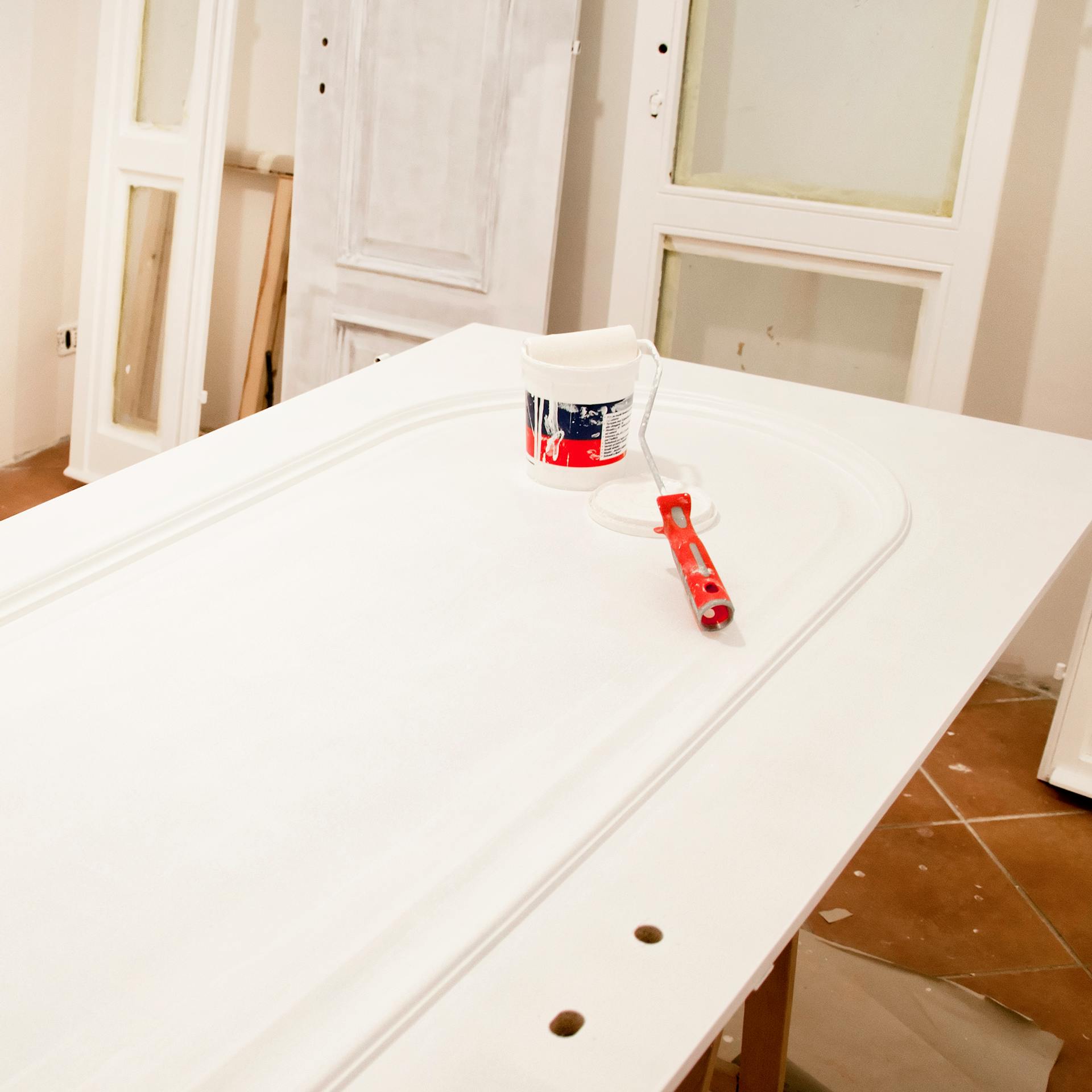 Porta bianca su cavalletti con secchio per pittura e rullo per pittura