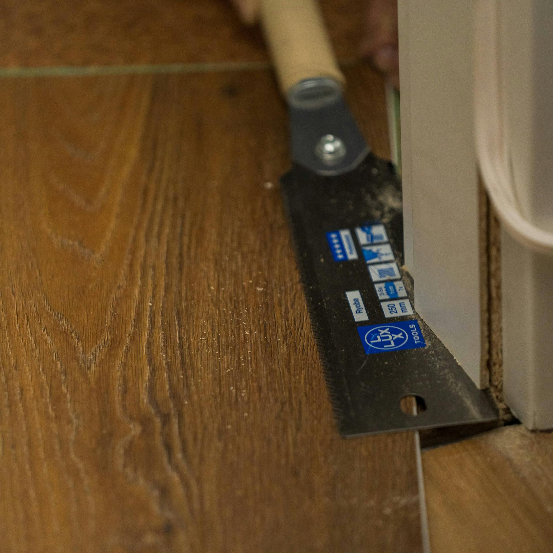 Jemand kürzt eine Türzarge mit einer Japansäge.