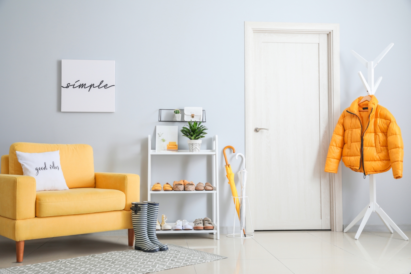 Zimmer mit gelber Couch und Garderobe. In der Mitte eine Weißlack-Tür