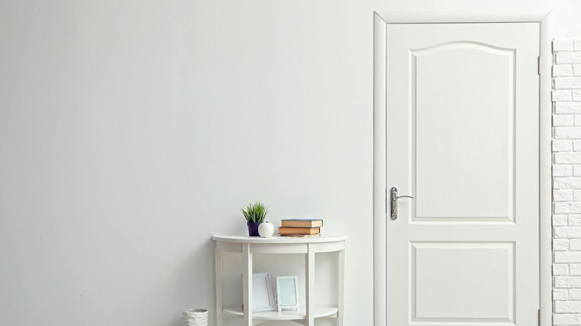 Weiße Zimmertür, daneben ein Beistelltisch.