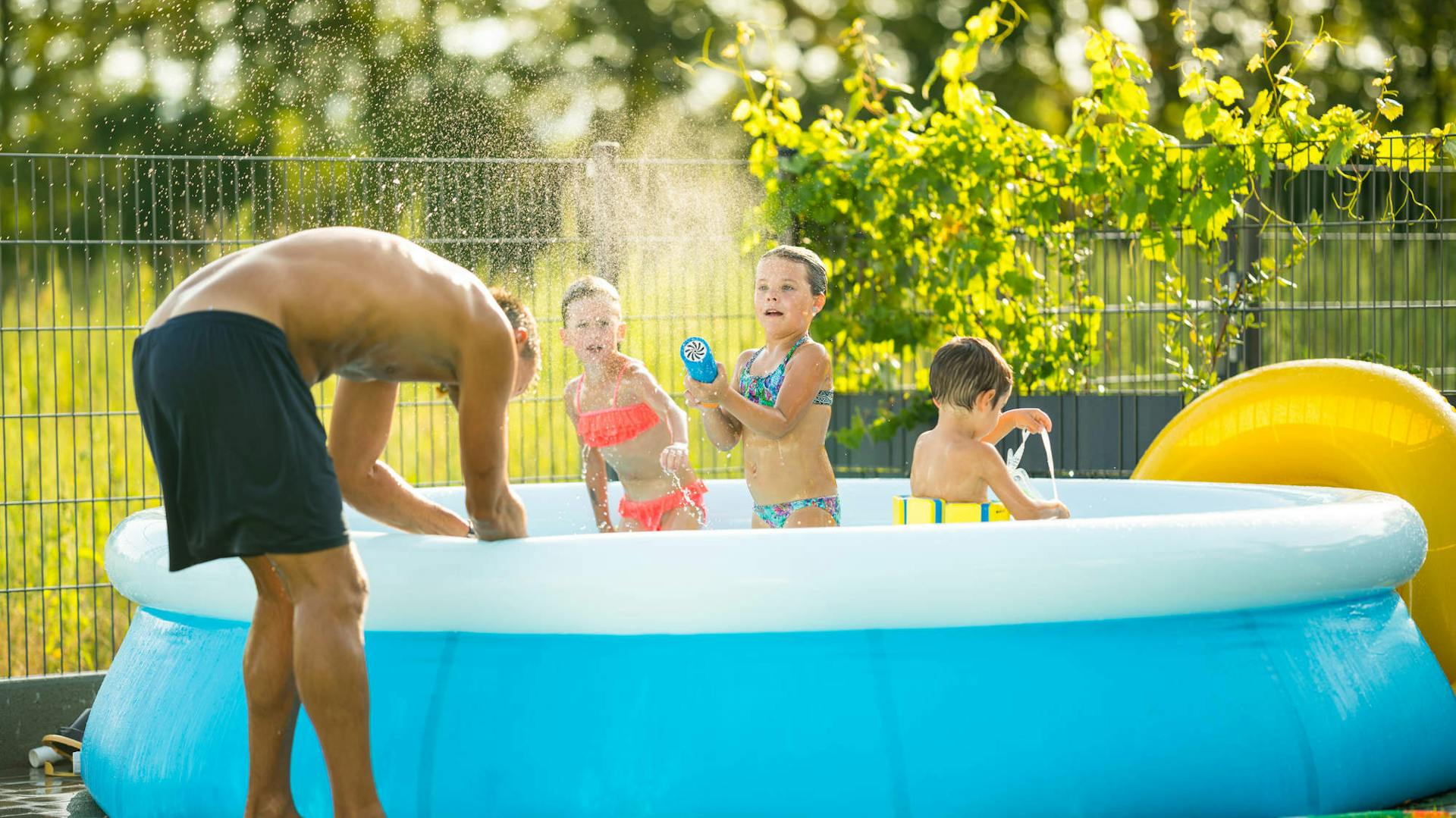 A gyerekek és apa a felfújható medencében szórakoznak.