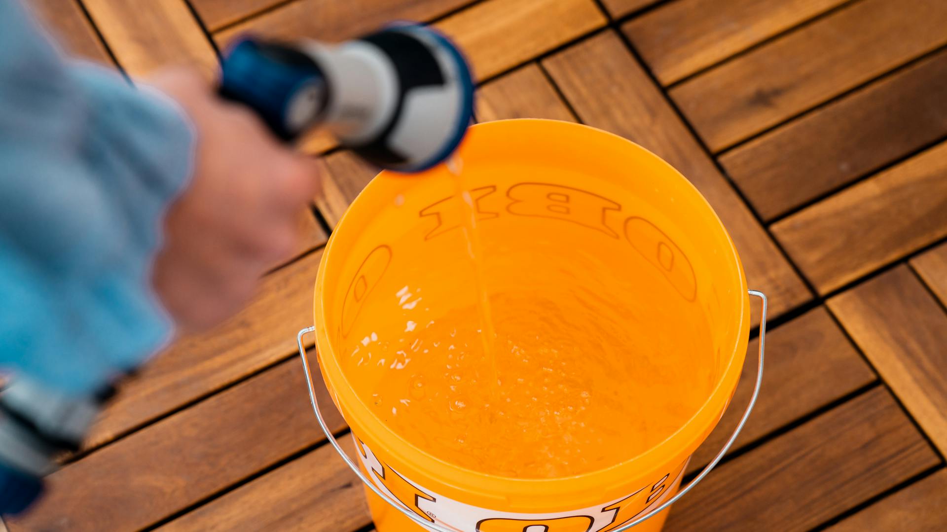 Ein Eimer wird mit einem Schlauch mit Wasser befüllt