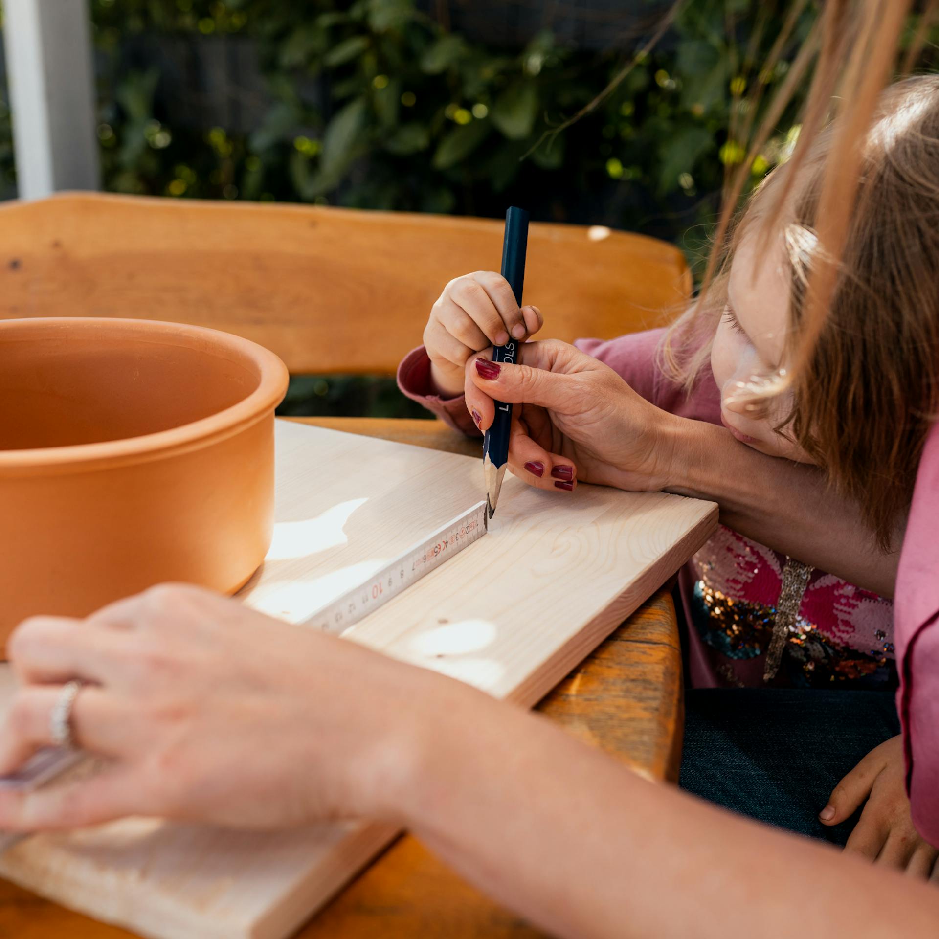 Frau zeichnet mit einem Bleistift auf einer Holzplatte ein Schnittmuster an
