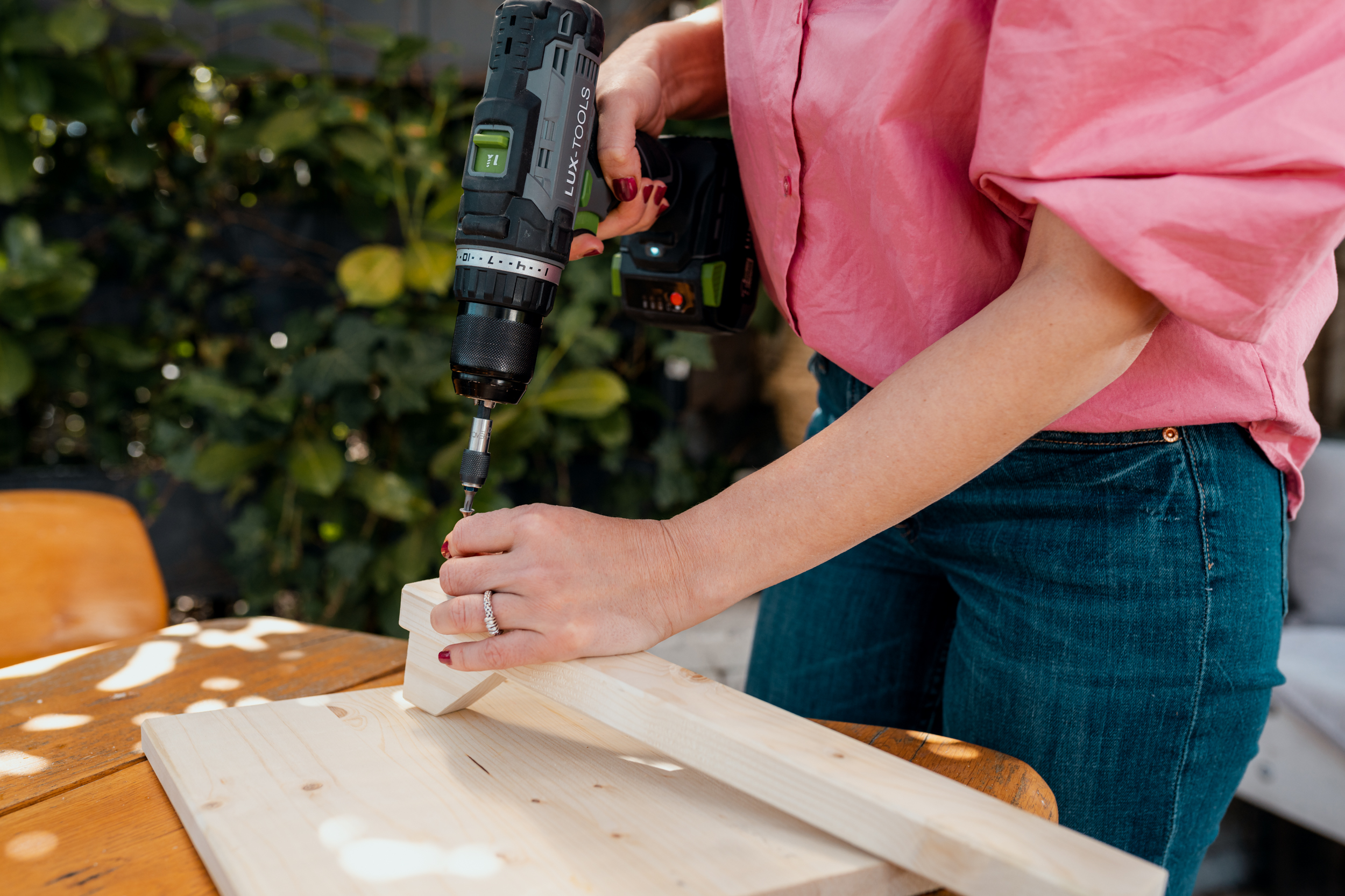 Donna fissa una vite su un profilo di legno con un avvitatore a batteria