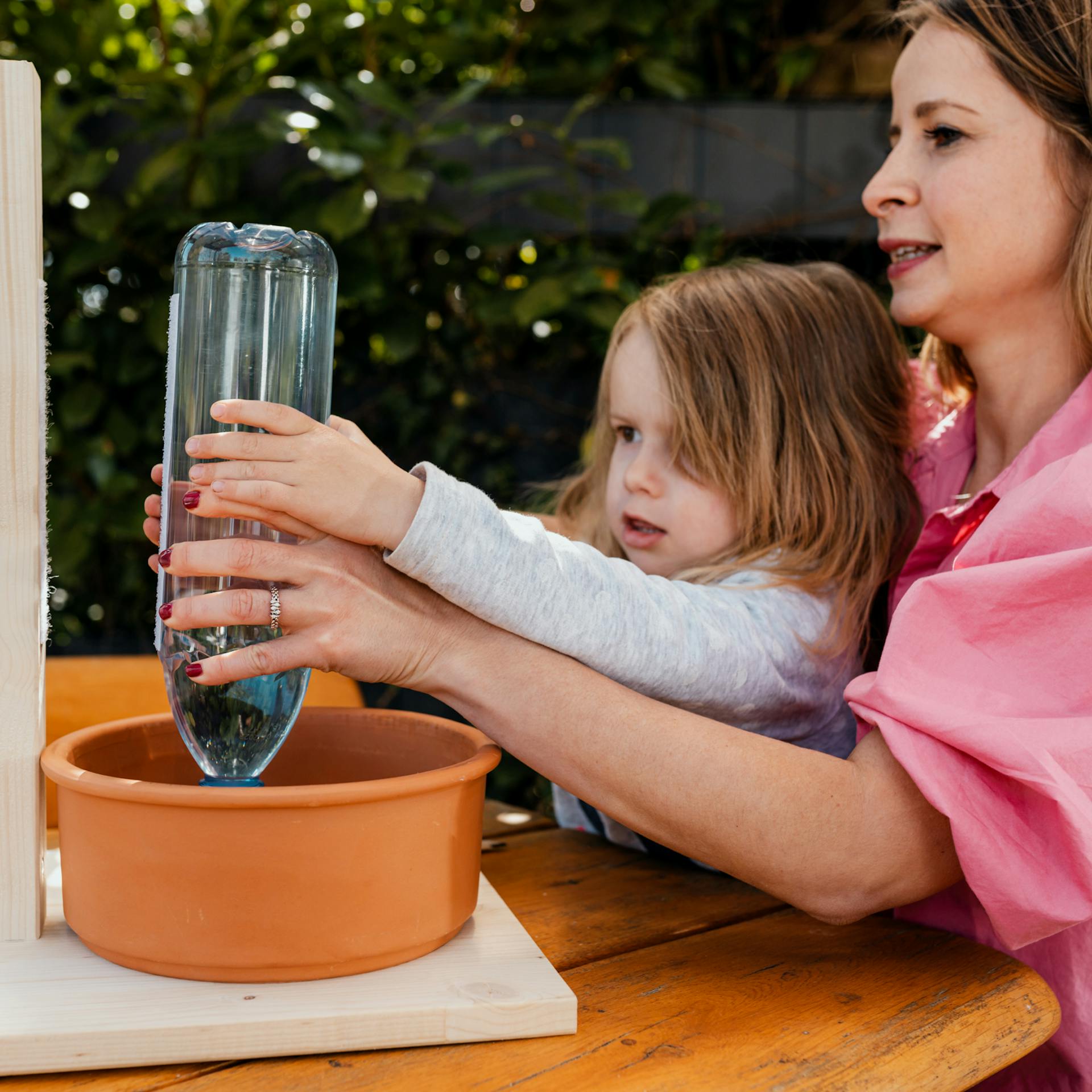 Mutter und Tochter bringen eine Flasche an einer Halterung über einem Hundenapf an