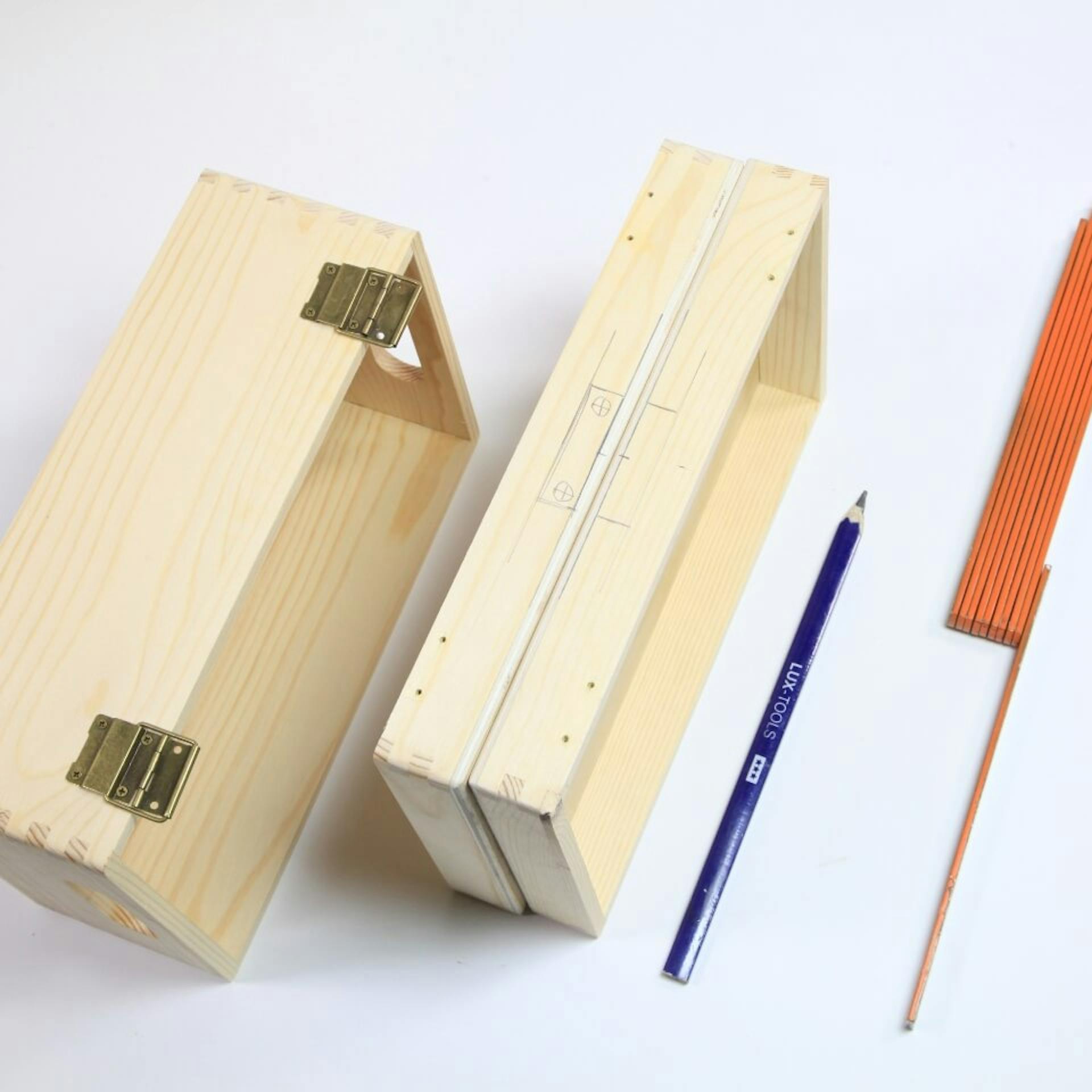 Holzkiste mit abgeschraubtem Deckel liegt neben Bleistift und Zollstock