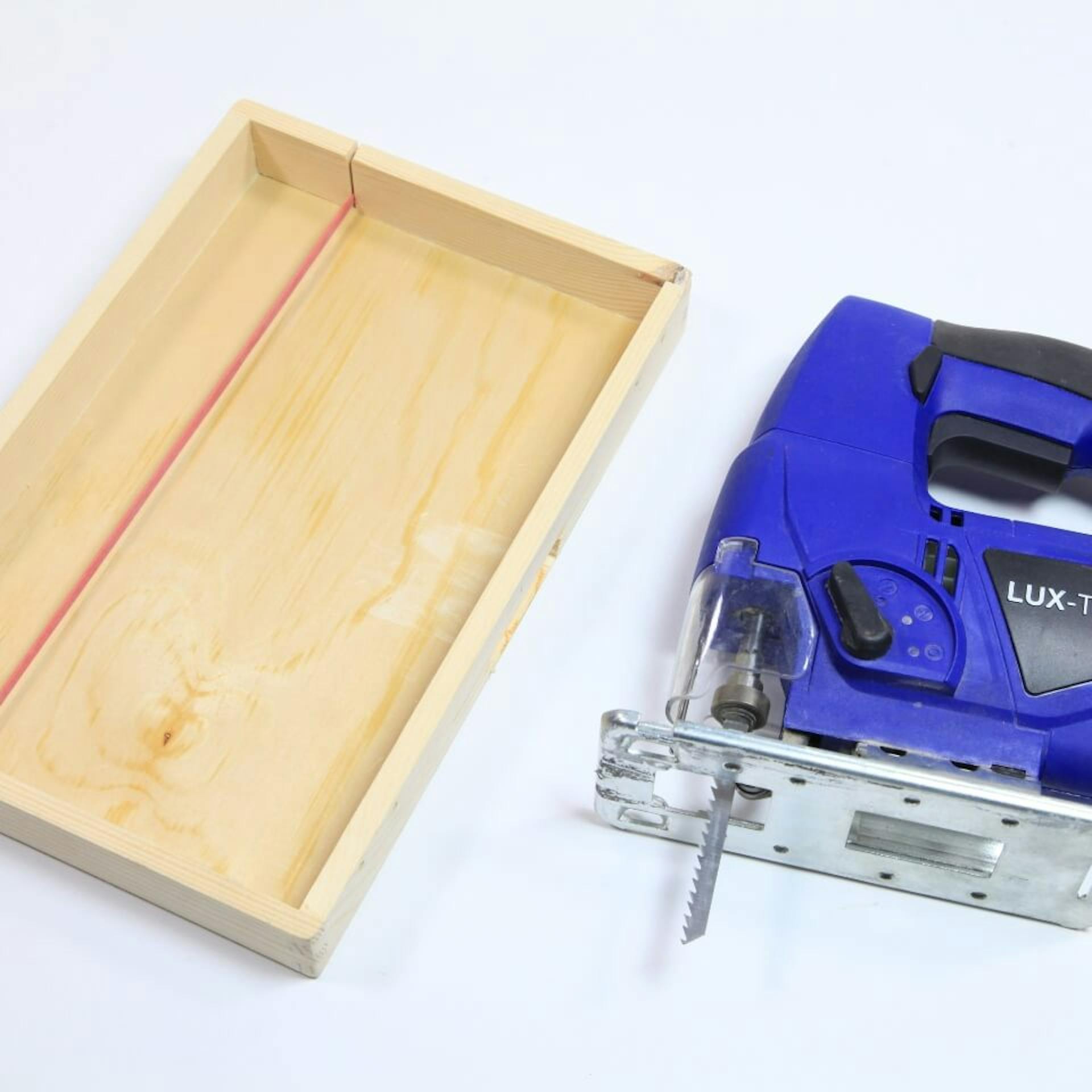 Stichsäge liegt neben Deckel aus Holz