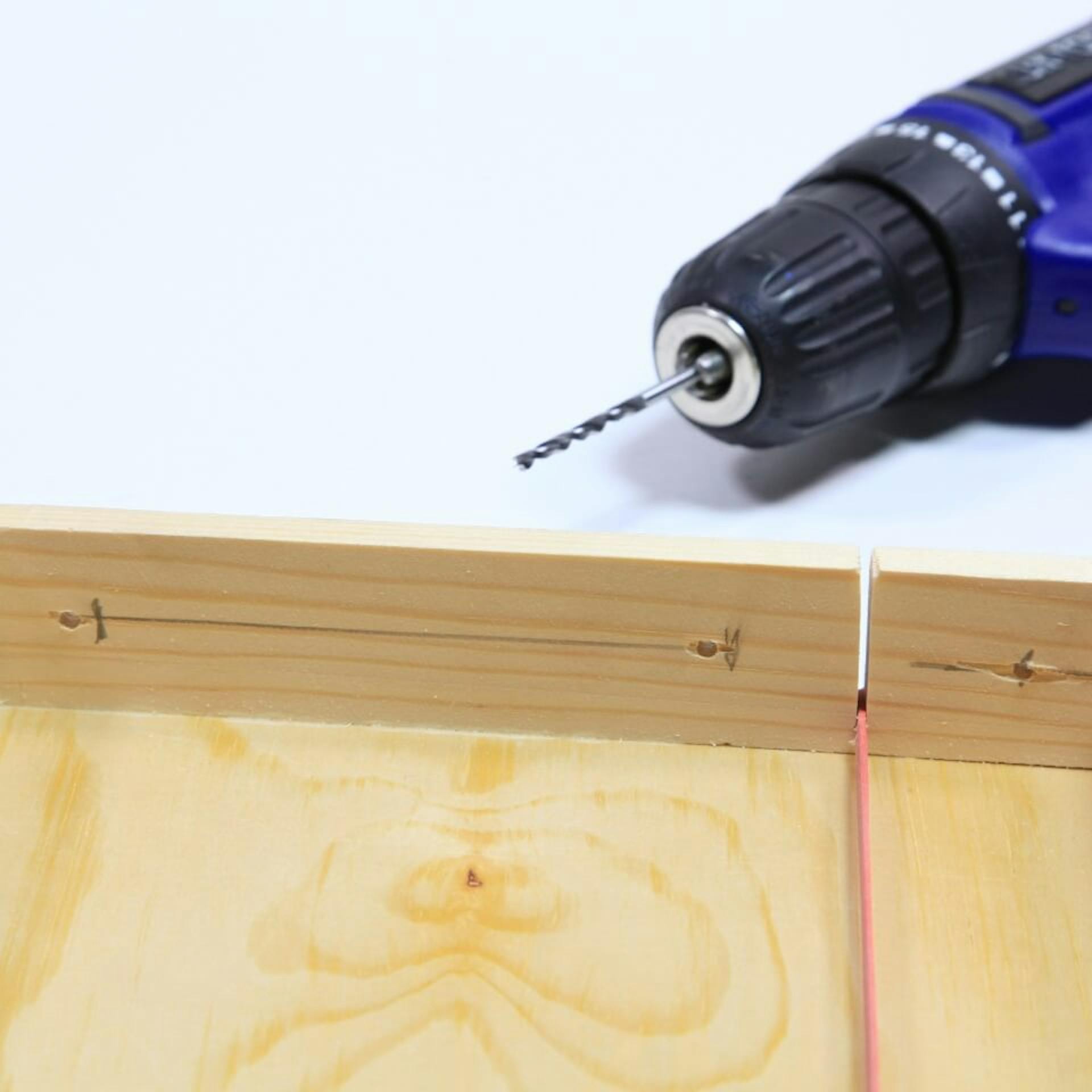 Akkuschrauber liegt neben Deckel aus Holz