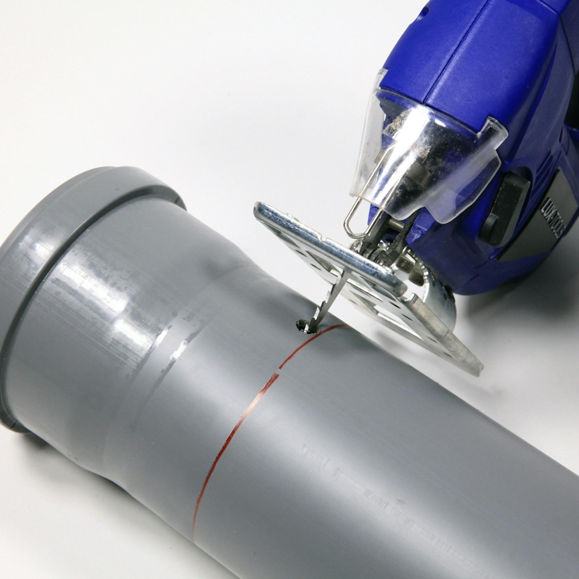 Stichsäge sägt Kopf des Abflussrohrs ab.