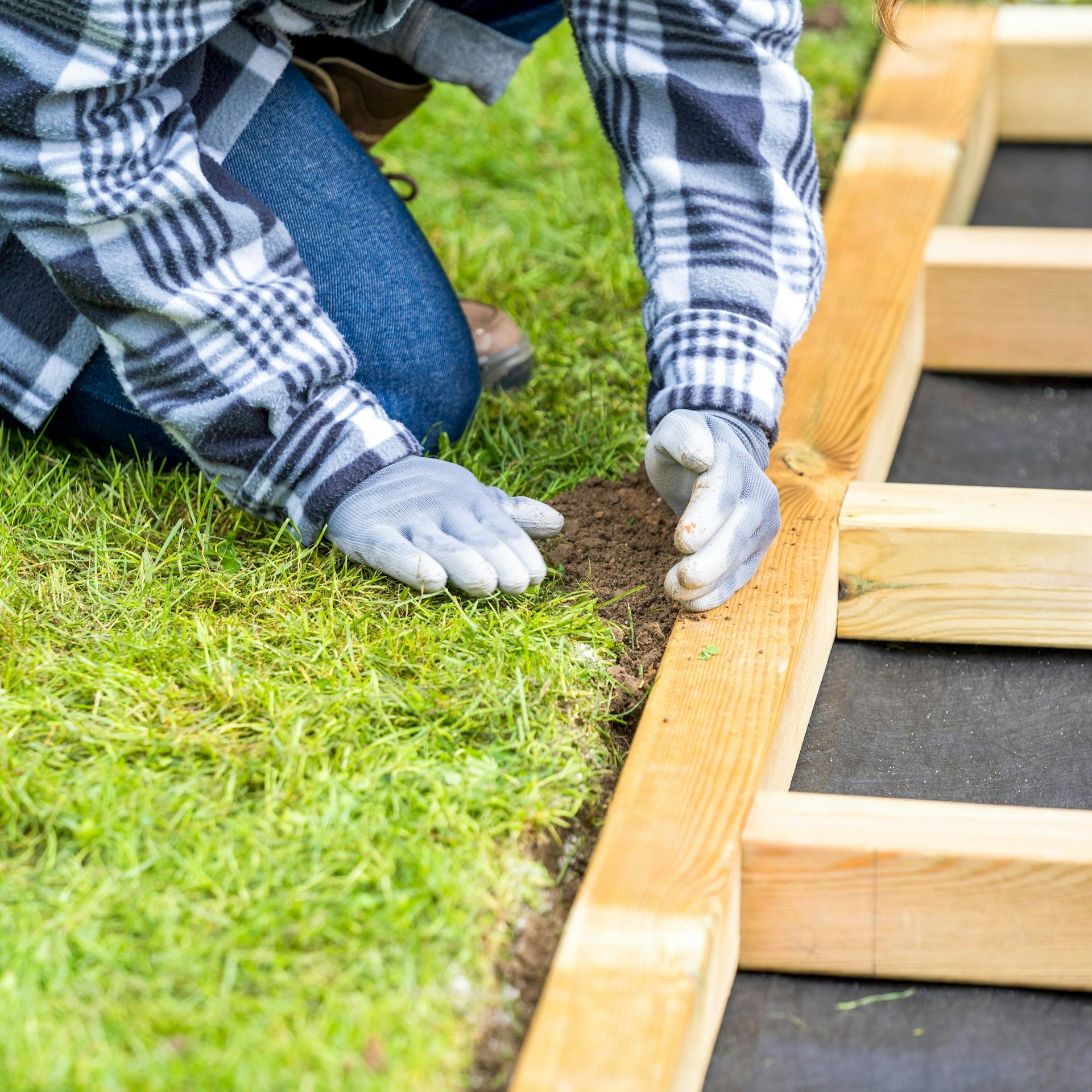 Einebnen von Barfußpfad durch Auffüllen von Lücken mit Erde