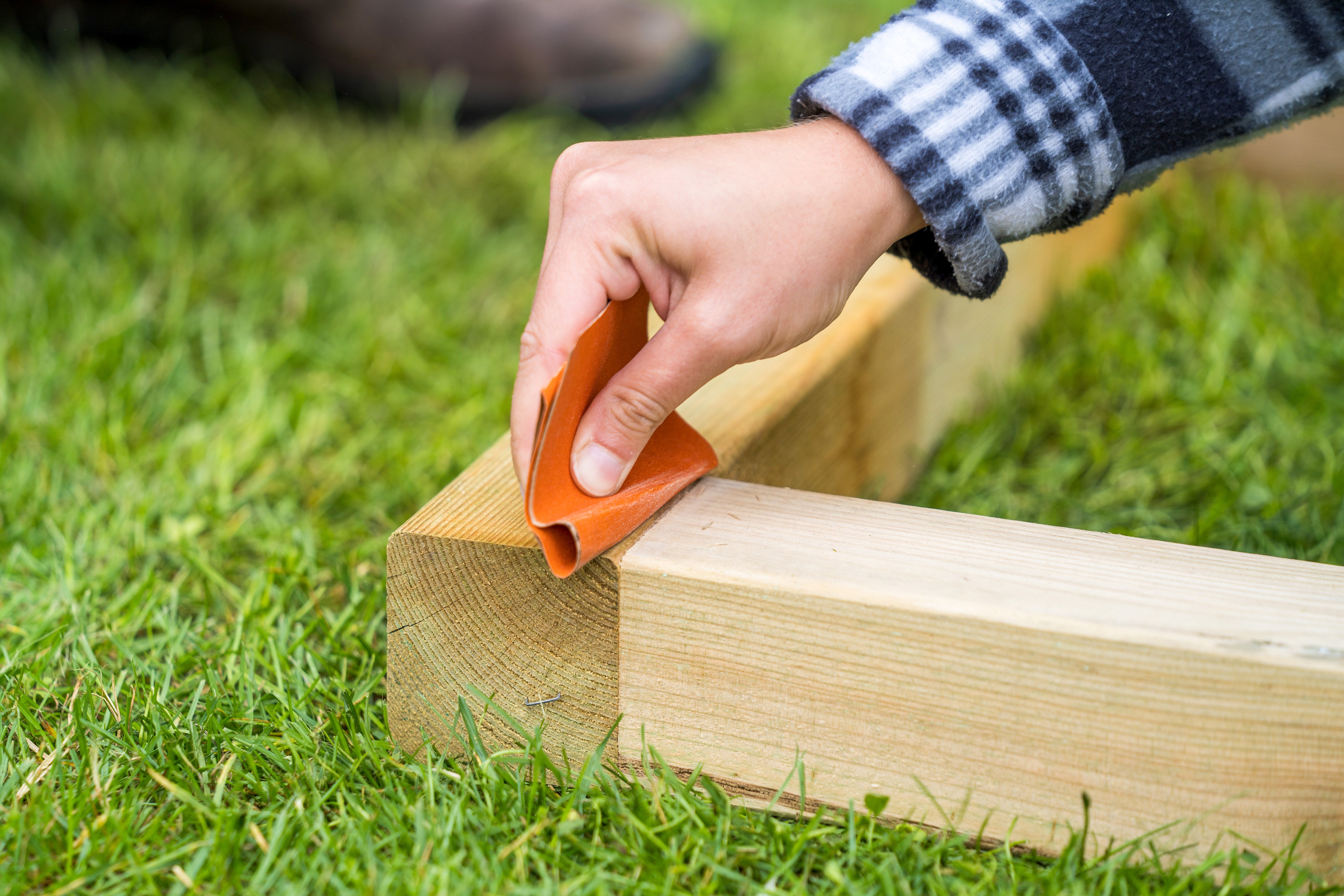 Heimwerkerin schleift Rahmen von Barfußpfad ab