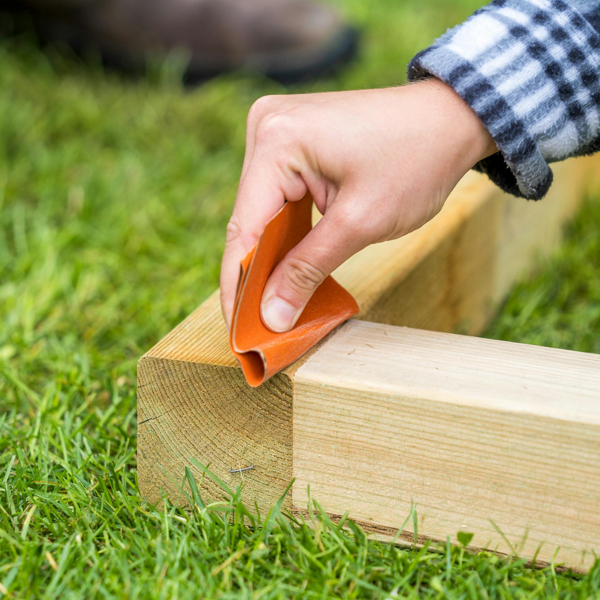 Heimwerkerin schleift Rahmen von Barfußpfad ab