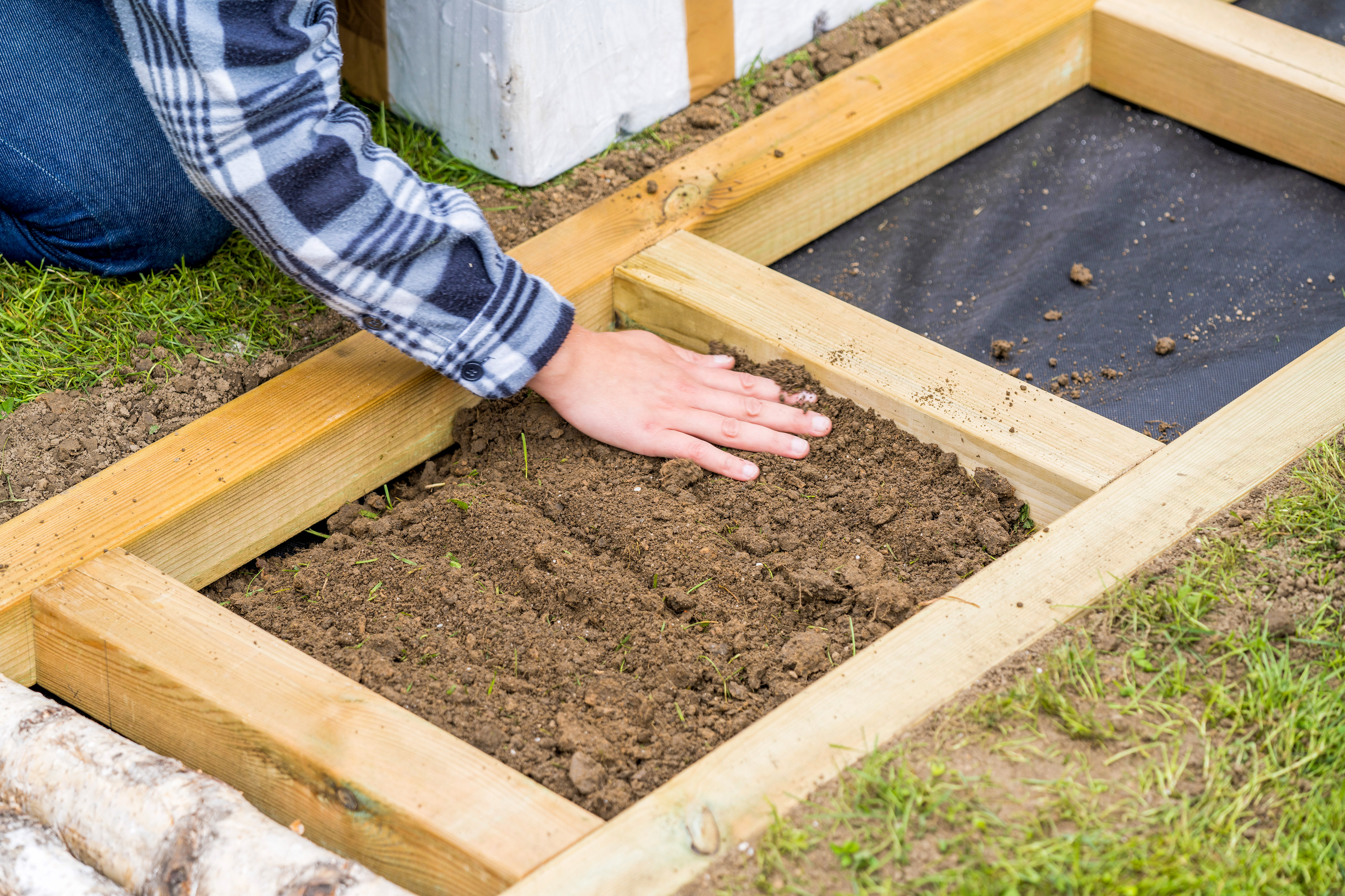 Erde wird in Barfußpfad gefüllt, um mögliche Stufen auszugleichen