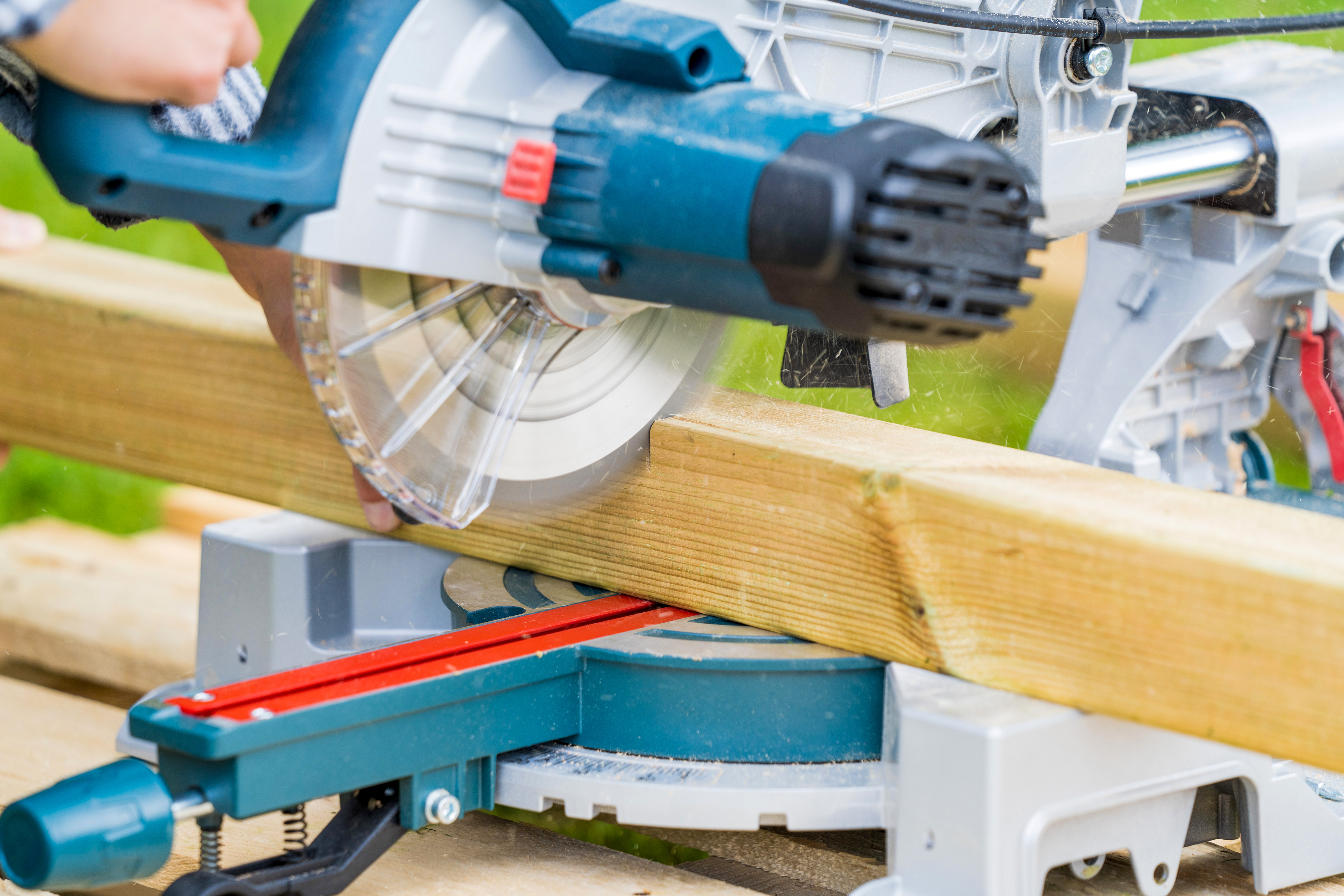 Heimwerkerin schneidet Balken für Barfußpfad mit Kapp- und Gehrungssäge zu