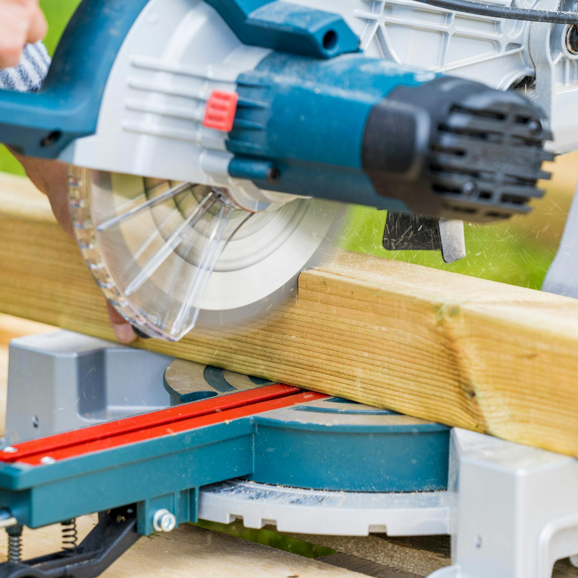 Heimwerkerin schneidet Balken für Barfußpfad mit Kapp- und Gehrungssäge zu