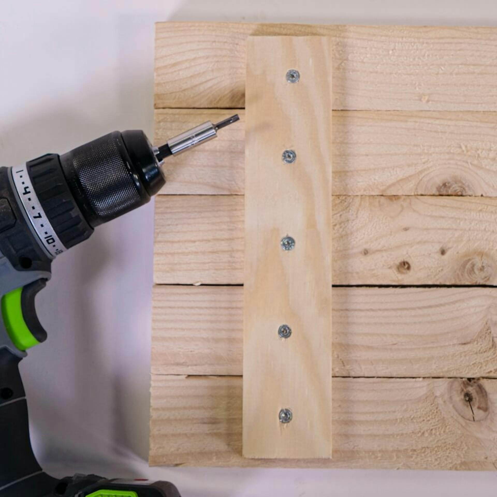 A kész, lécekből készült hátlap egy asztalon fekszik. Mellette van egy akkus csavarhúzó.