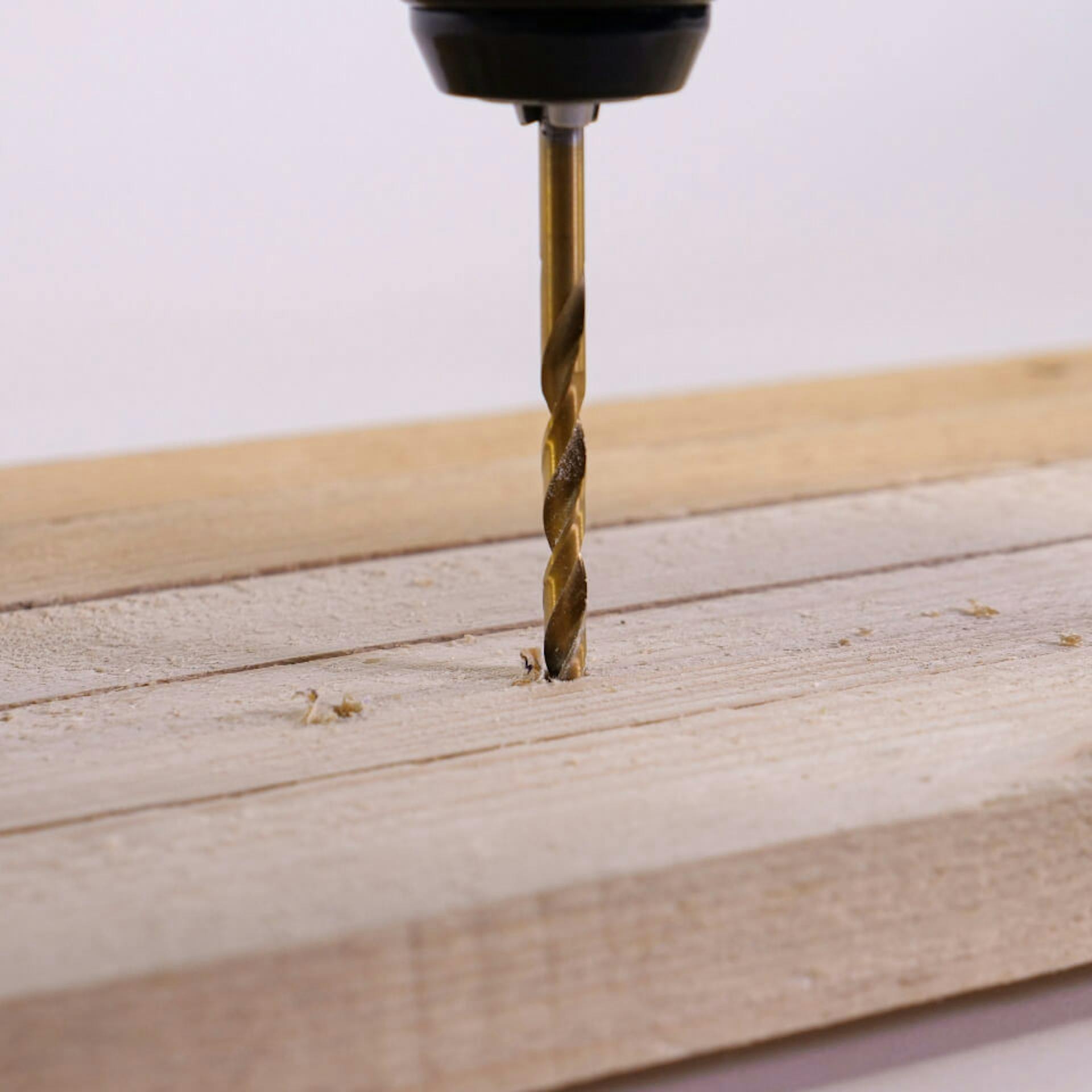 Egy személy lyukakat fúr egy fatáblába.