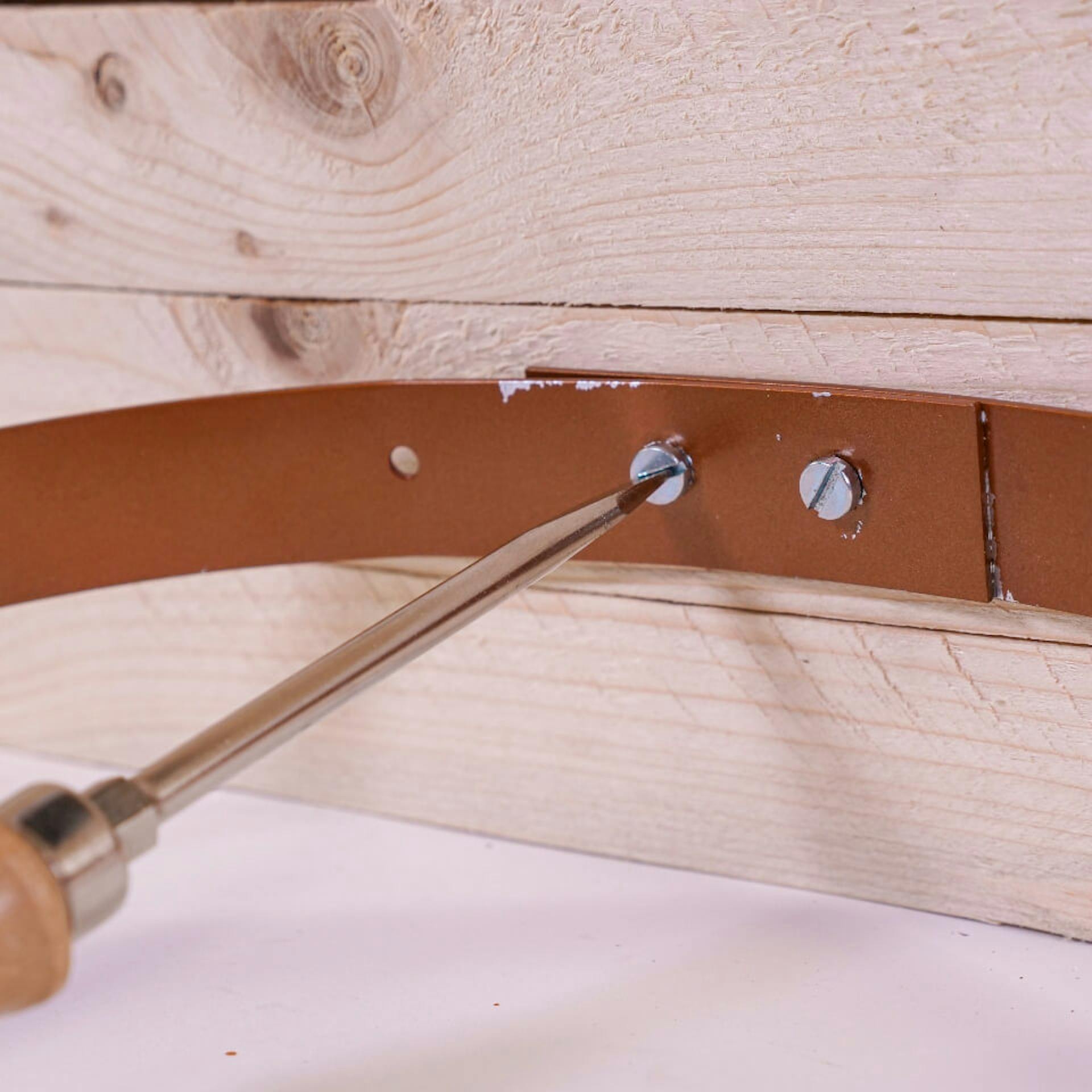 A személy az alumíniumgyűrűt csavarokkal rögzíti a fatáblához.