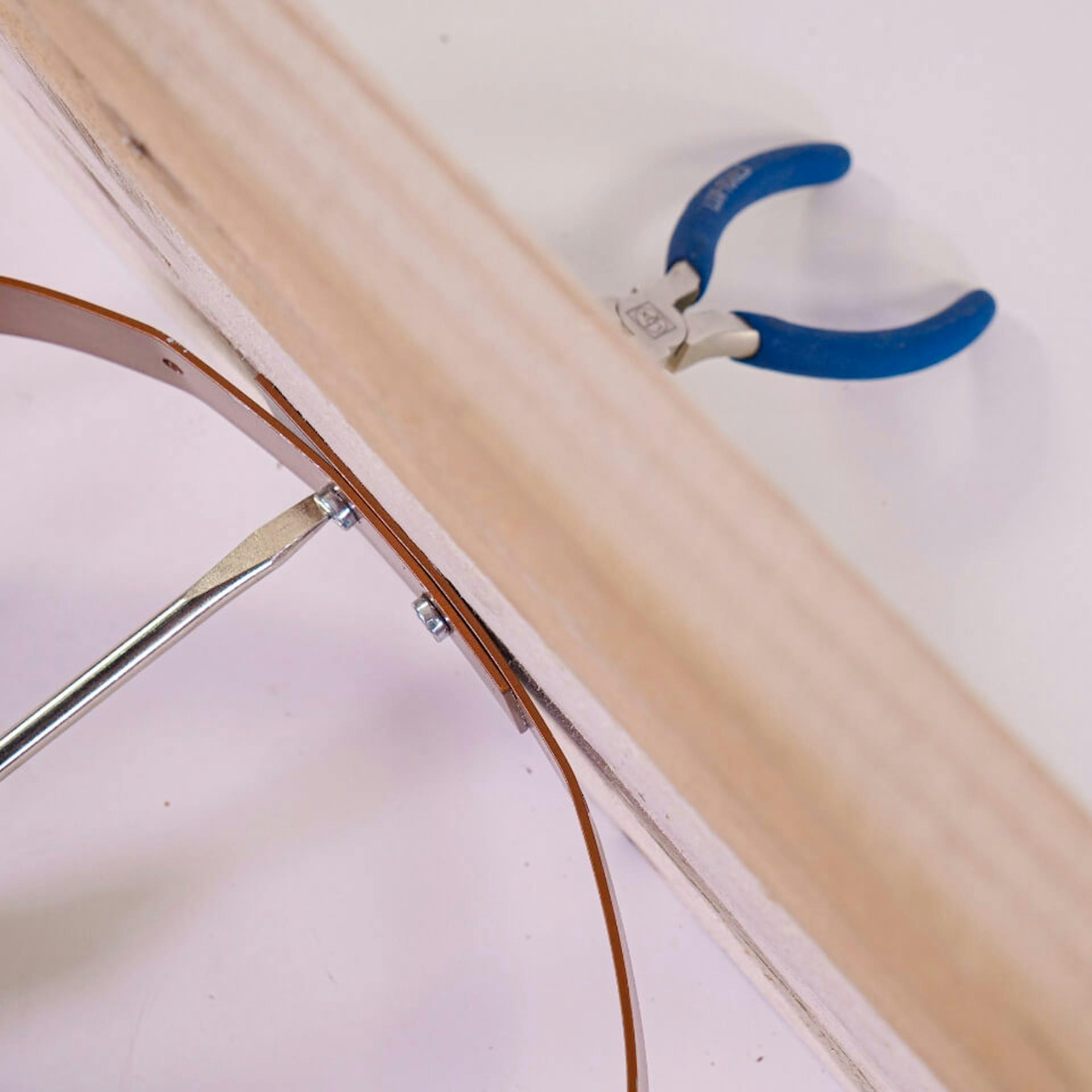 Fából készült csík, amelyhez alumíniumgyűrűt csavaroznak. Az egyik oldalon egy fogó tartja a csavart a helyén, a másik oldalon pedig egy csavarhúzó.