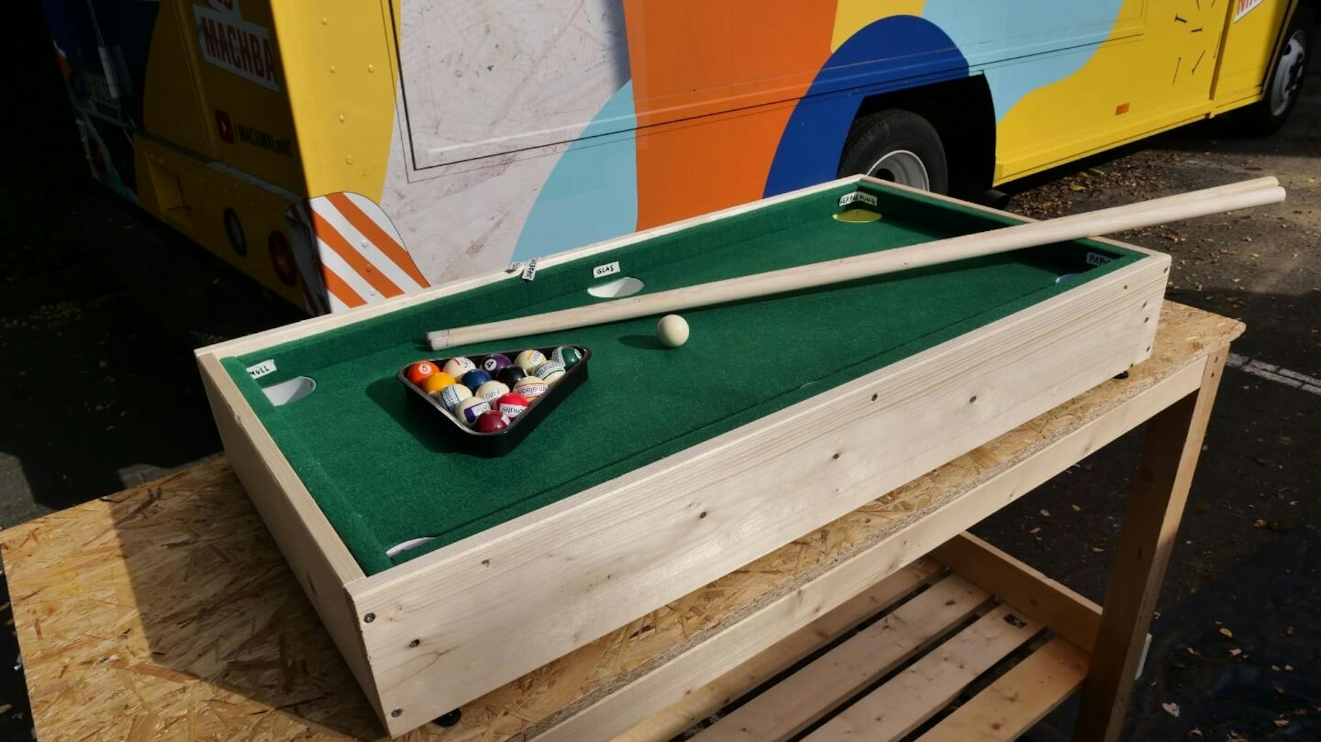 Kleiner Billardtisch mit Kugeln und Billardqueue liegt auf einer Tischplatte