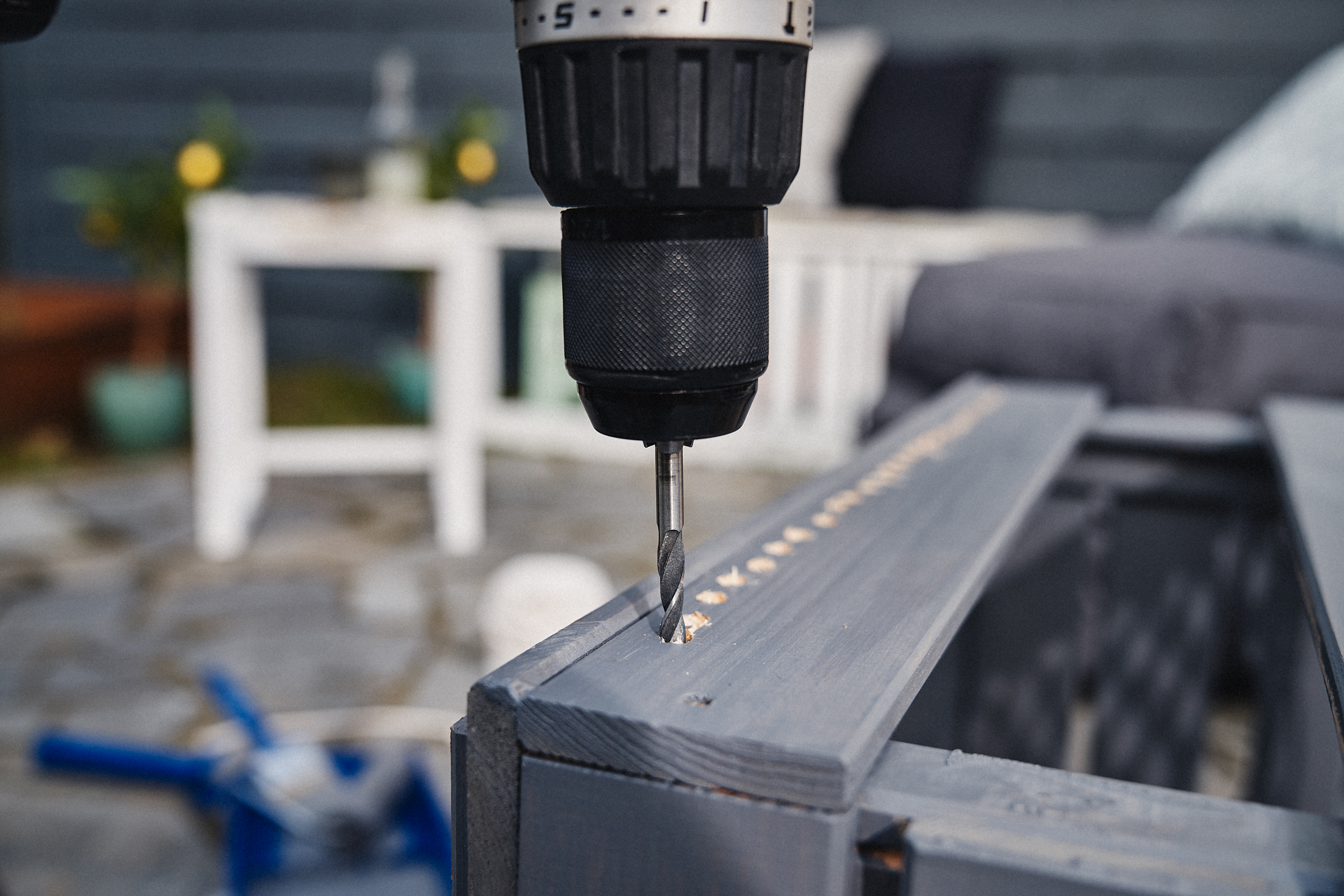 Egy fúrógép lyukakat fúr a fadobozba