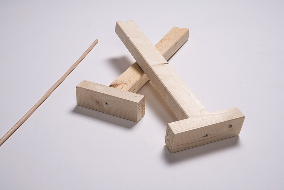 Zwei Holzlatten verschraubt mit Holzstücken, daneben liegt ein Holzstab.