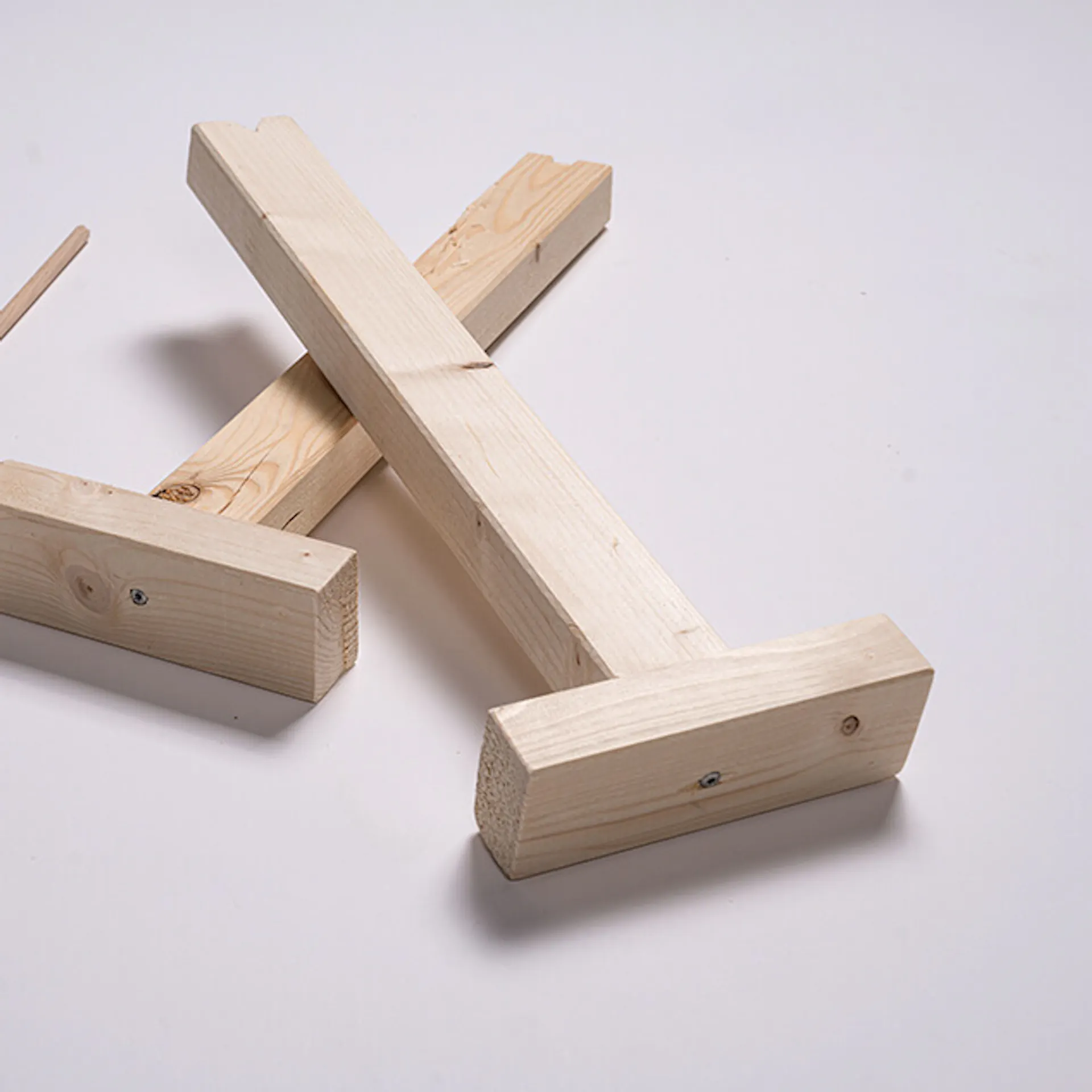 Zwei Holzlatten verschraubt mit Holzstücken, daneben liegt ein Holzstab.