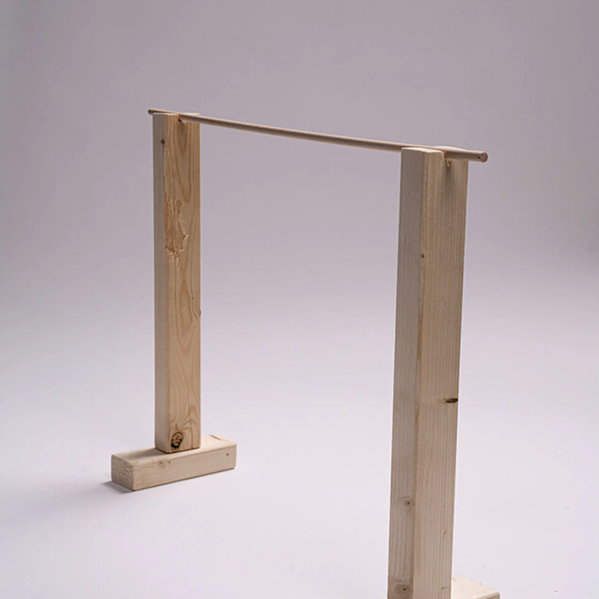 Zwei Holzlatten auf Holzstücken, darauf liegt ein Holzstab.